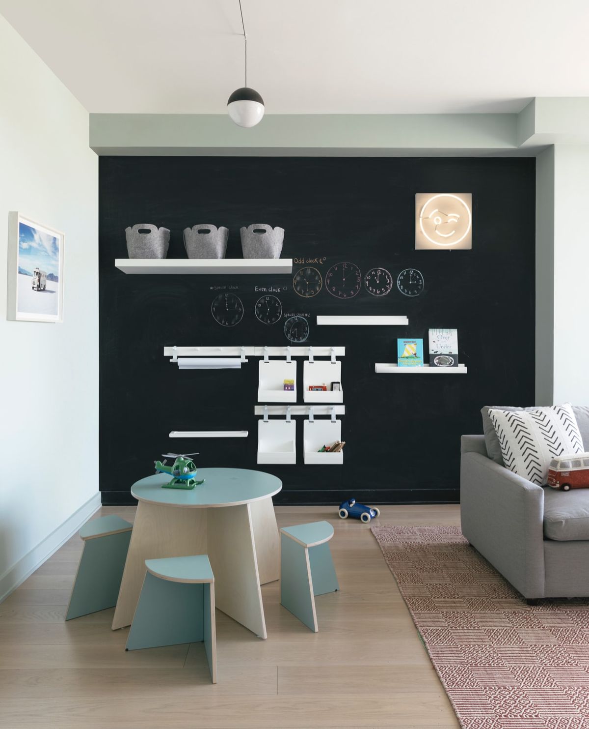 Child's play area. Chalkboard paint wall with shelves for storage and kid's play table next to sofa