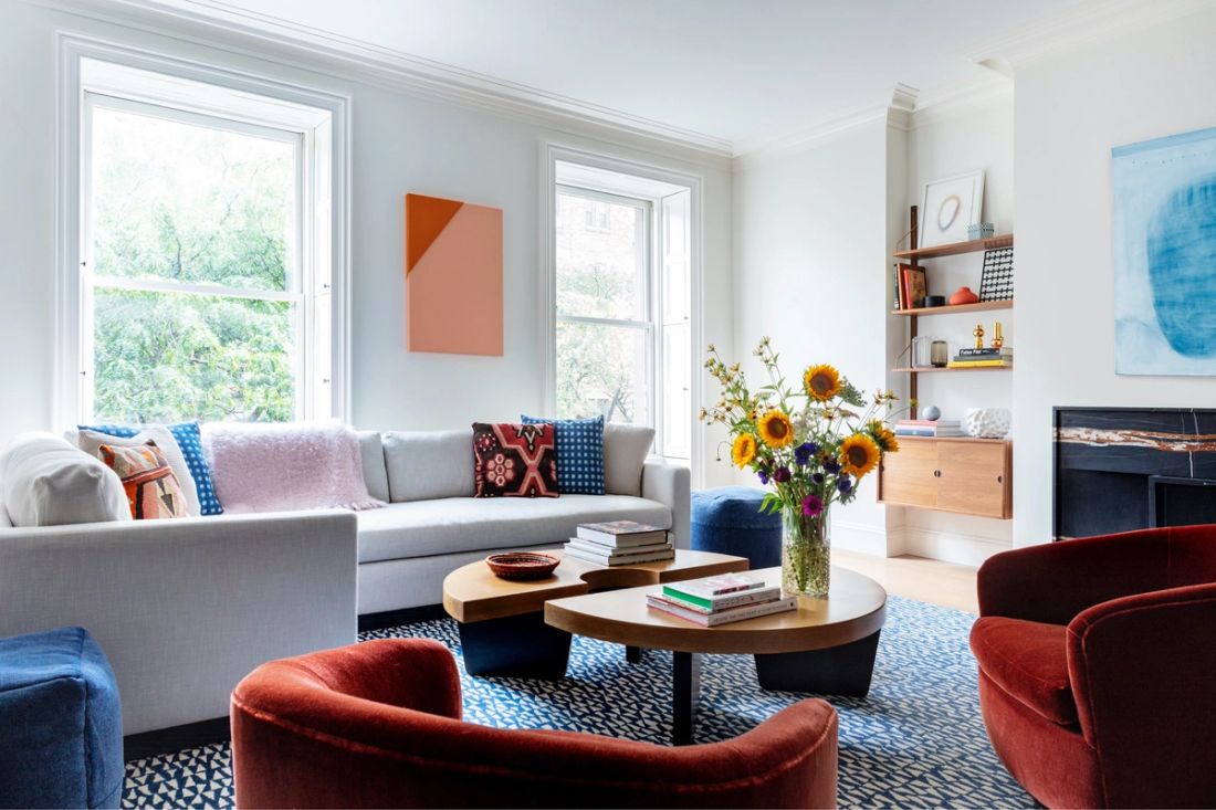 Living room with sofa, chairs, coffee table, shelves, fireplace and windows