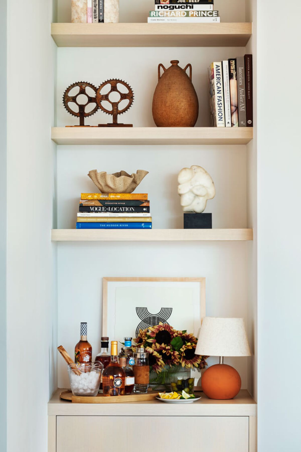 Shelving built into the wall above matching cabinet holds books and acts as bar area
