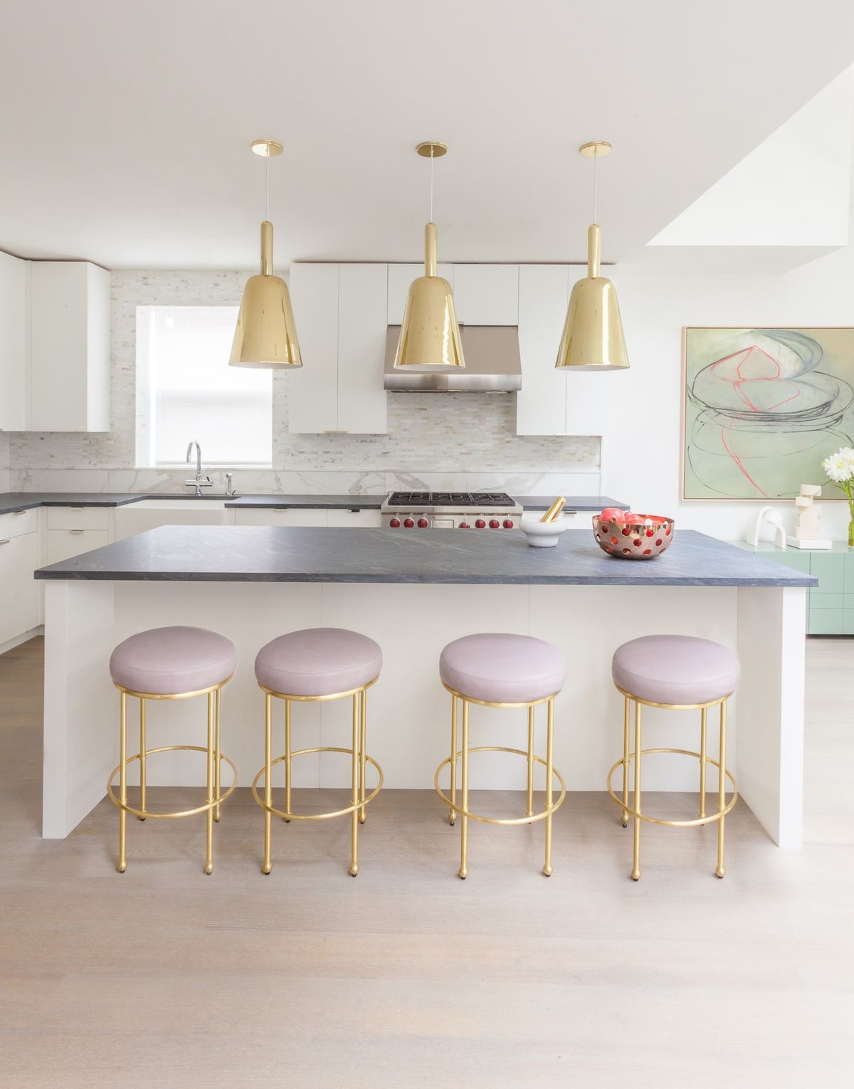Large, open-plan kitchen with large gold pendants above the island, and lavender-cushioned counter stools