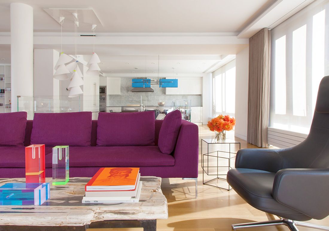 Plum-colored sofa in foreground of open floor plan of kitchen/dining/living room