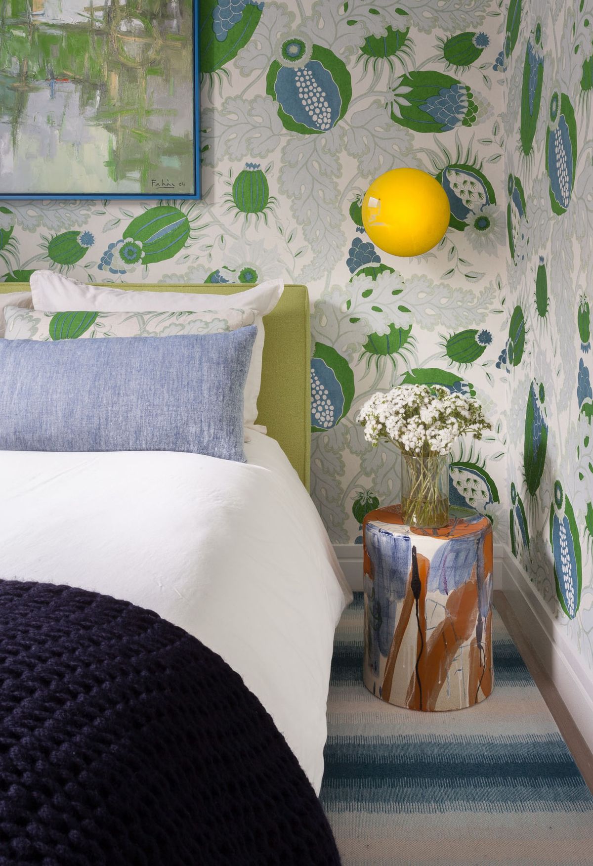 detail of guest bed and side table with patterned floral wallpaper