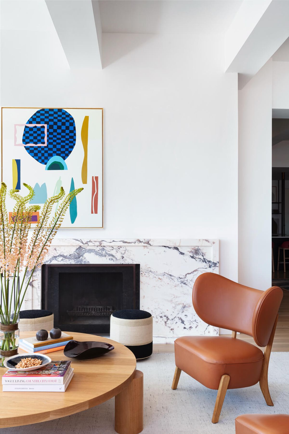 Detail of fireplace with coffee table and leather side chairs and poufs and contemporary surrealist art