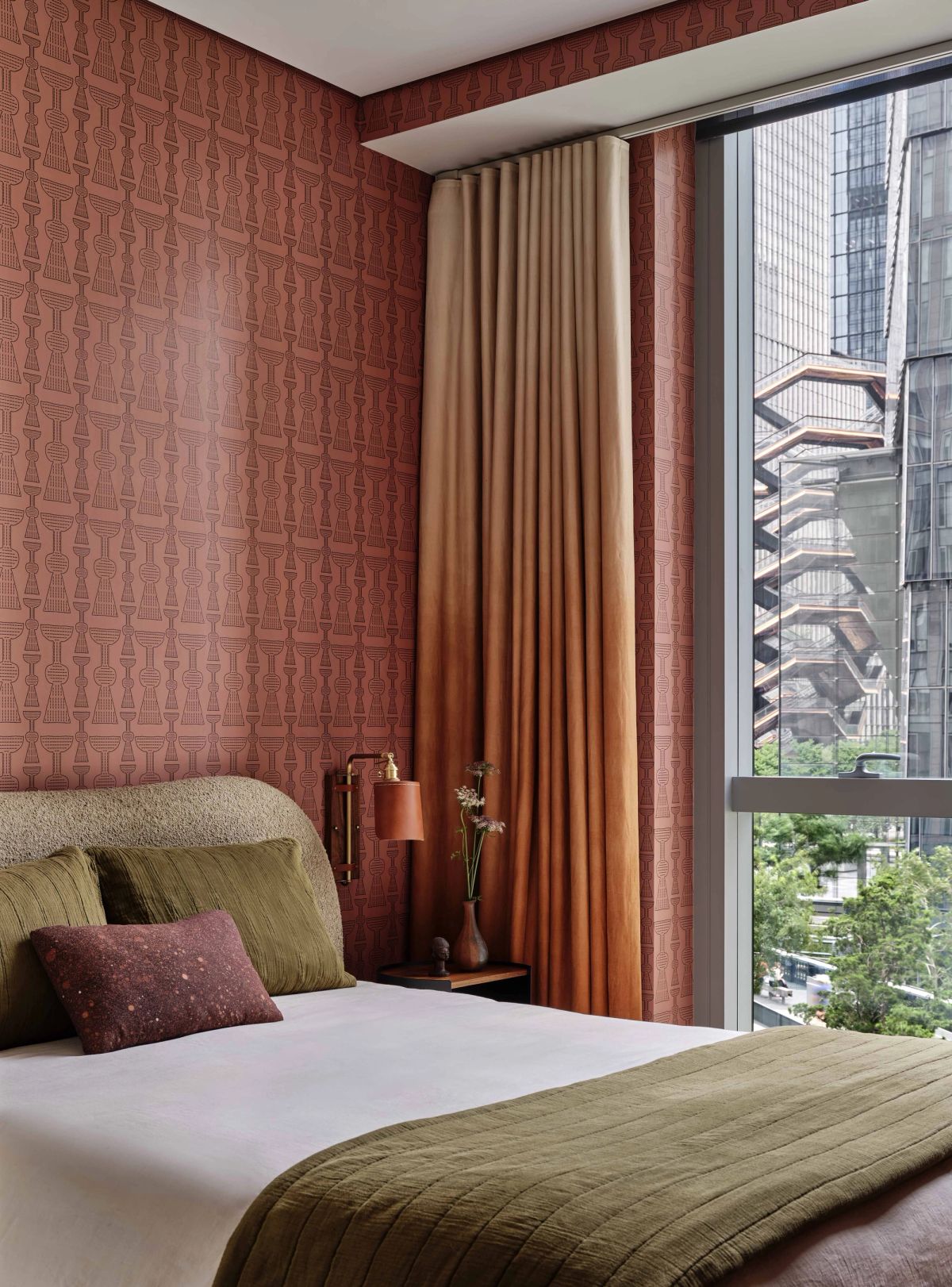 Guest bedroom with terra cotta patterned wallcovering and cream and olive bedding