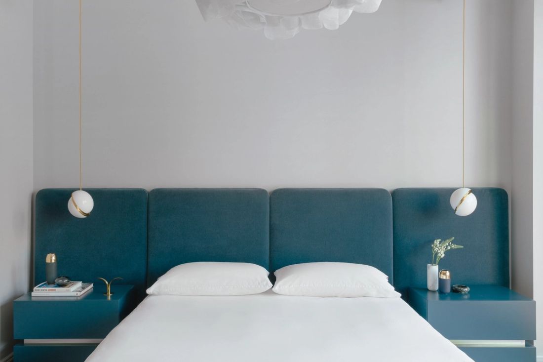Primary bedroom with custom velvet headboard and integrated side tables and pendant lighting