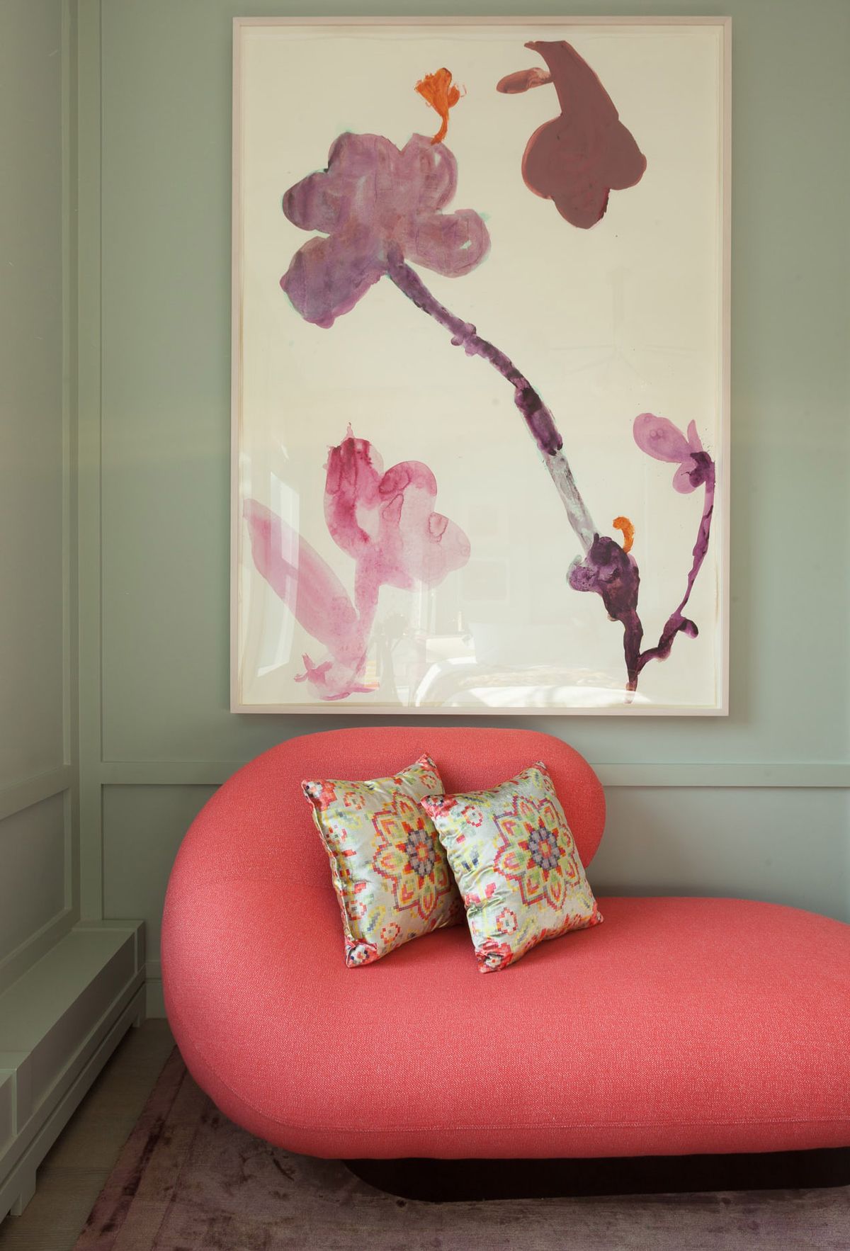 Custom curvalinear-shaped coral colored sofa with accent pillows beneath large color-field artwork