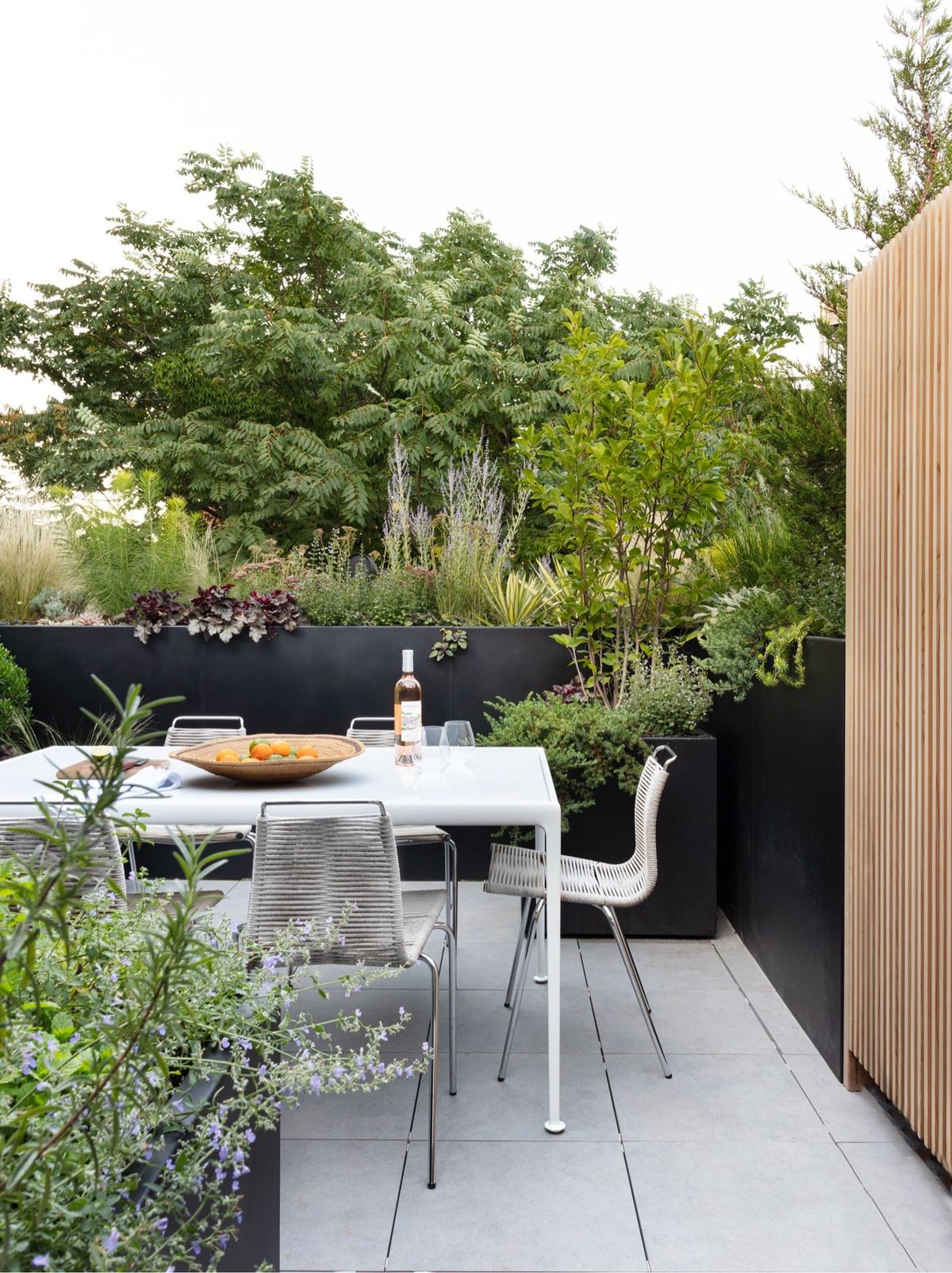 Rooftop deck dining area surrounded by lush plantings