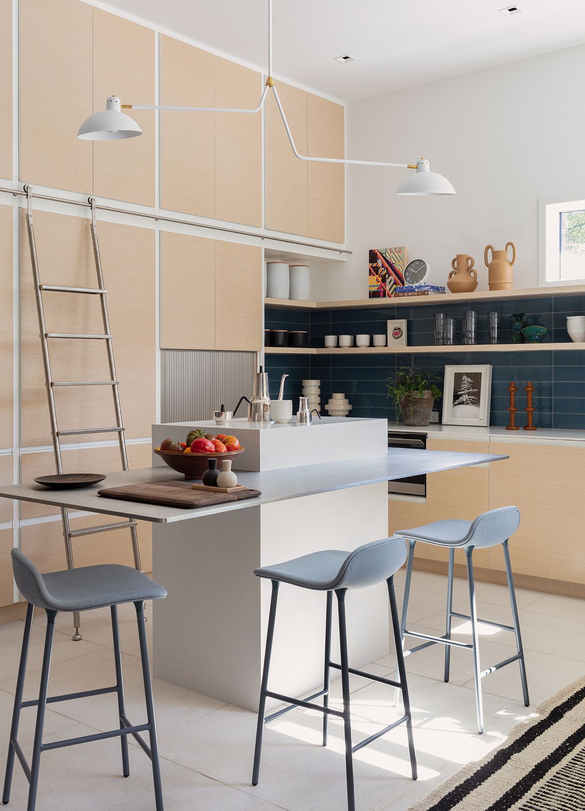 Kitchen island detail with counter stools, fruit on counter, and objects on shelves
