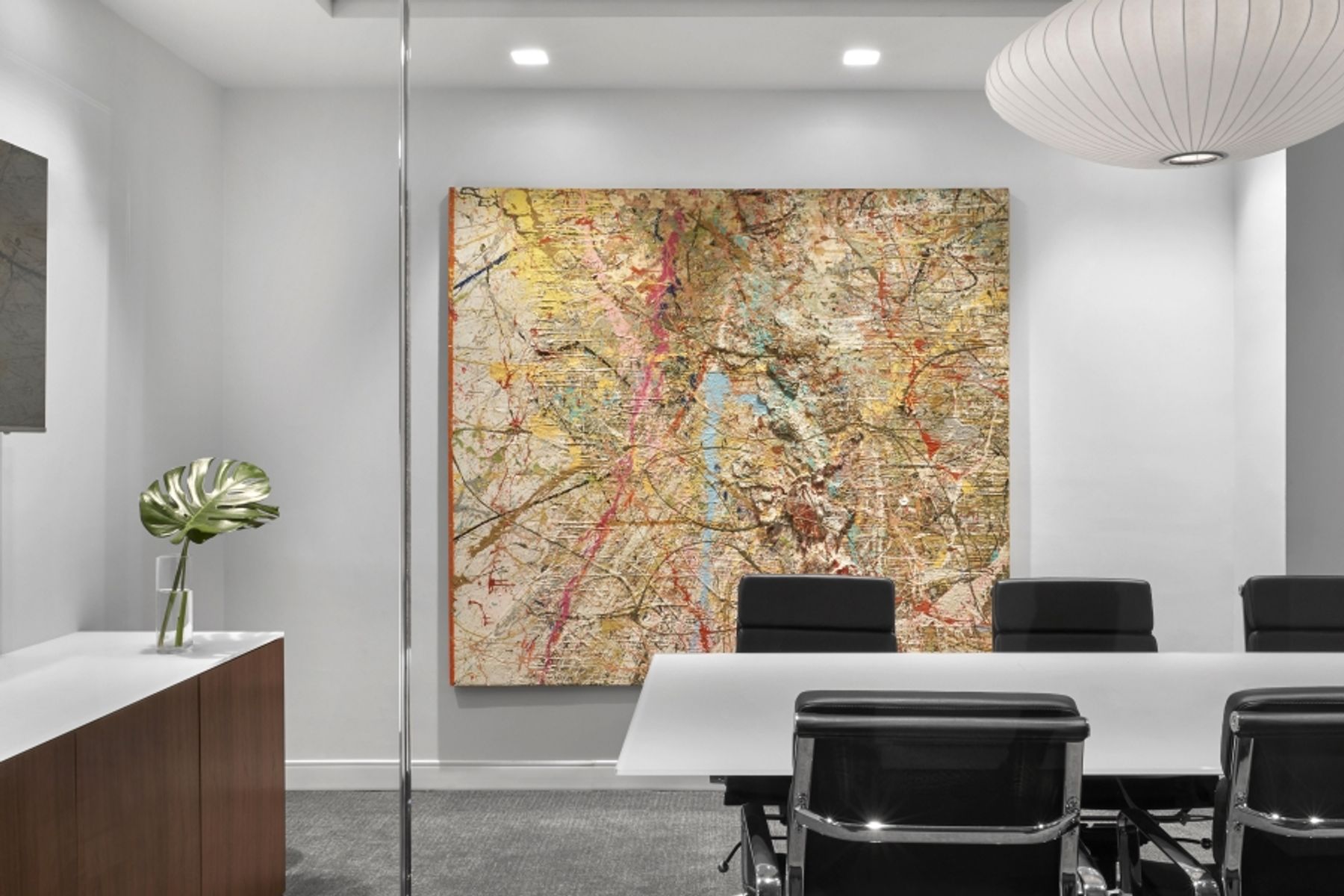 Conference room with white conference table, black leather chairs and abstract, textural artwork