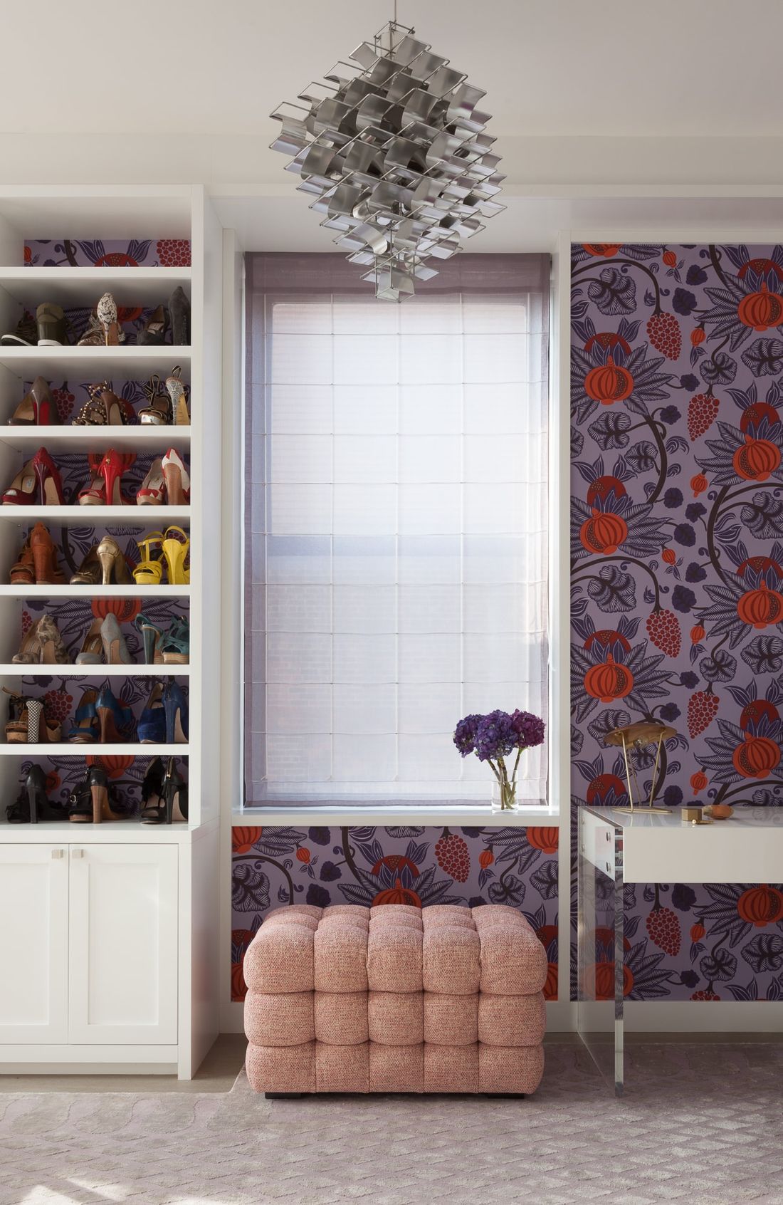 Walk-in closet with vanity, patterned wallpaper in hues of purple and red and built-in shoe cabinet
