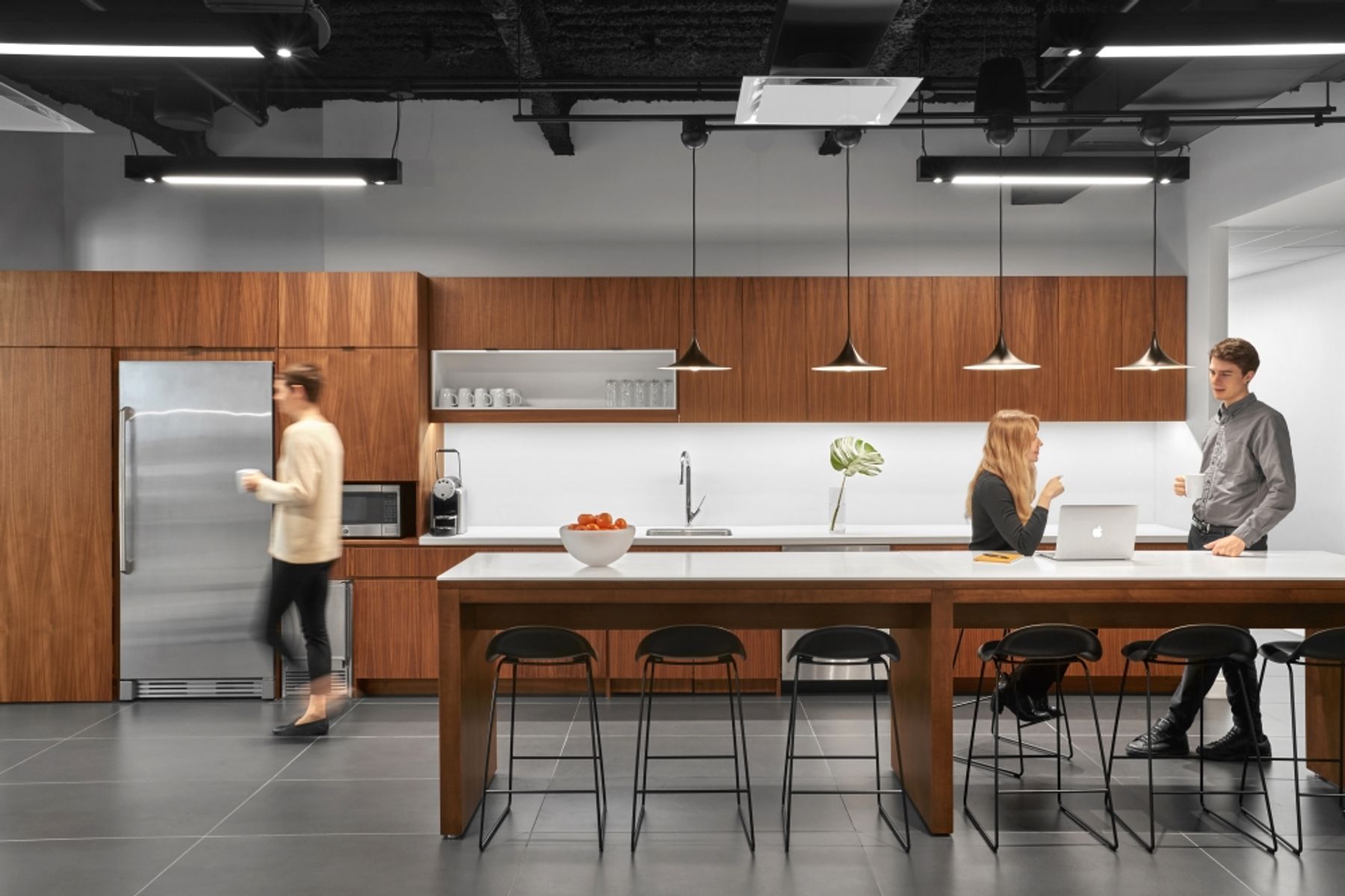Kitchen with warm wood cabinets, gray tiled flooring, countertop seating and stainless steel appliances