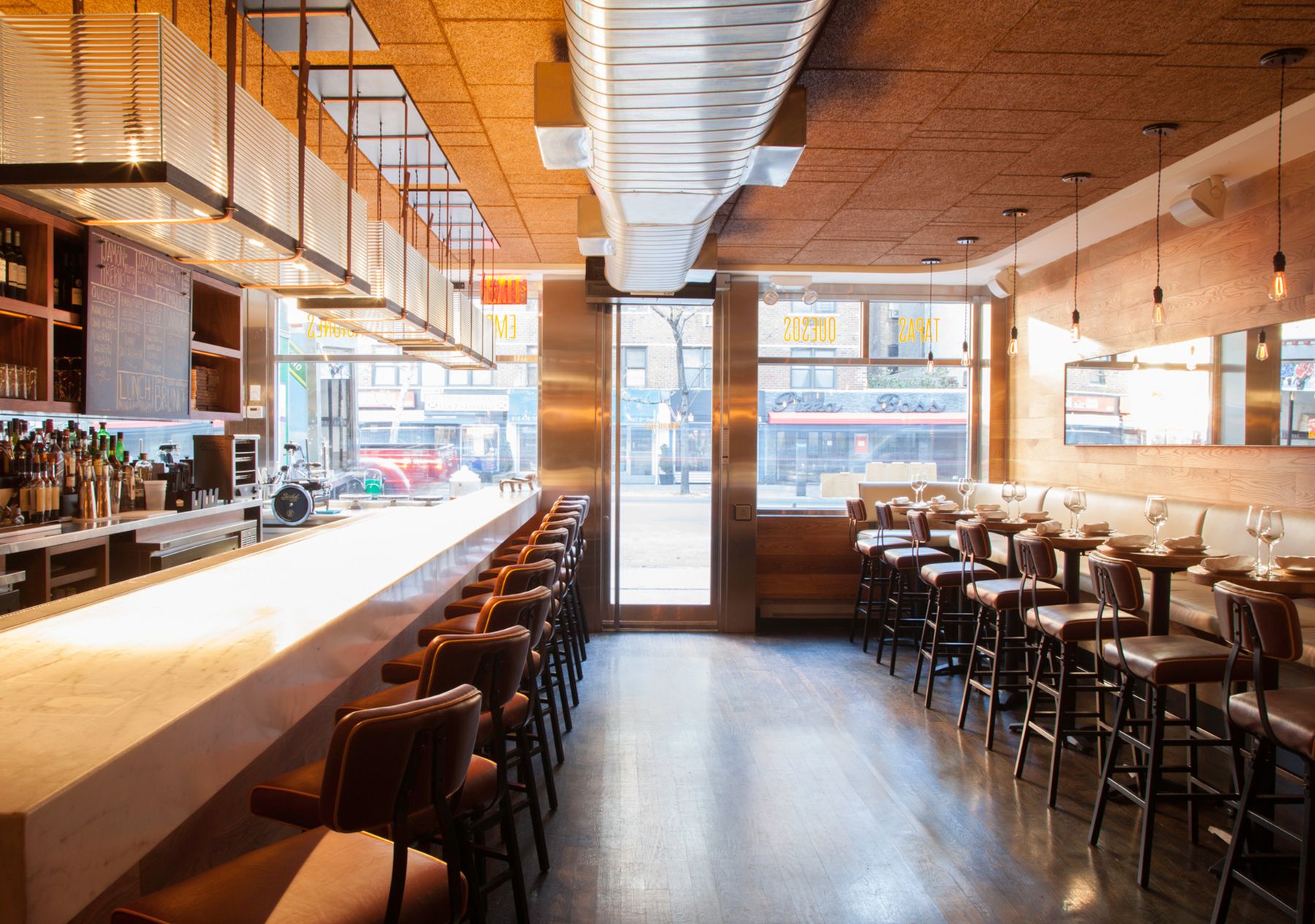 View of dining room looking out to the street. The bar is on the left and the banquette, high-top seating is on the right
