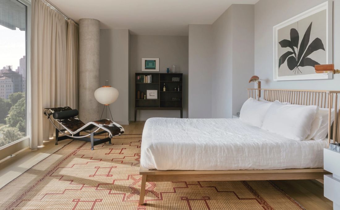 Primary bedroom with king-sized wood frame with wall-sized window of view of Central Park
