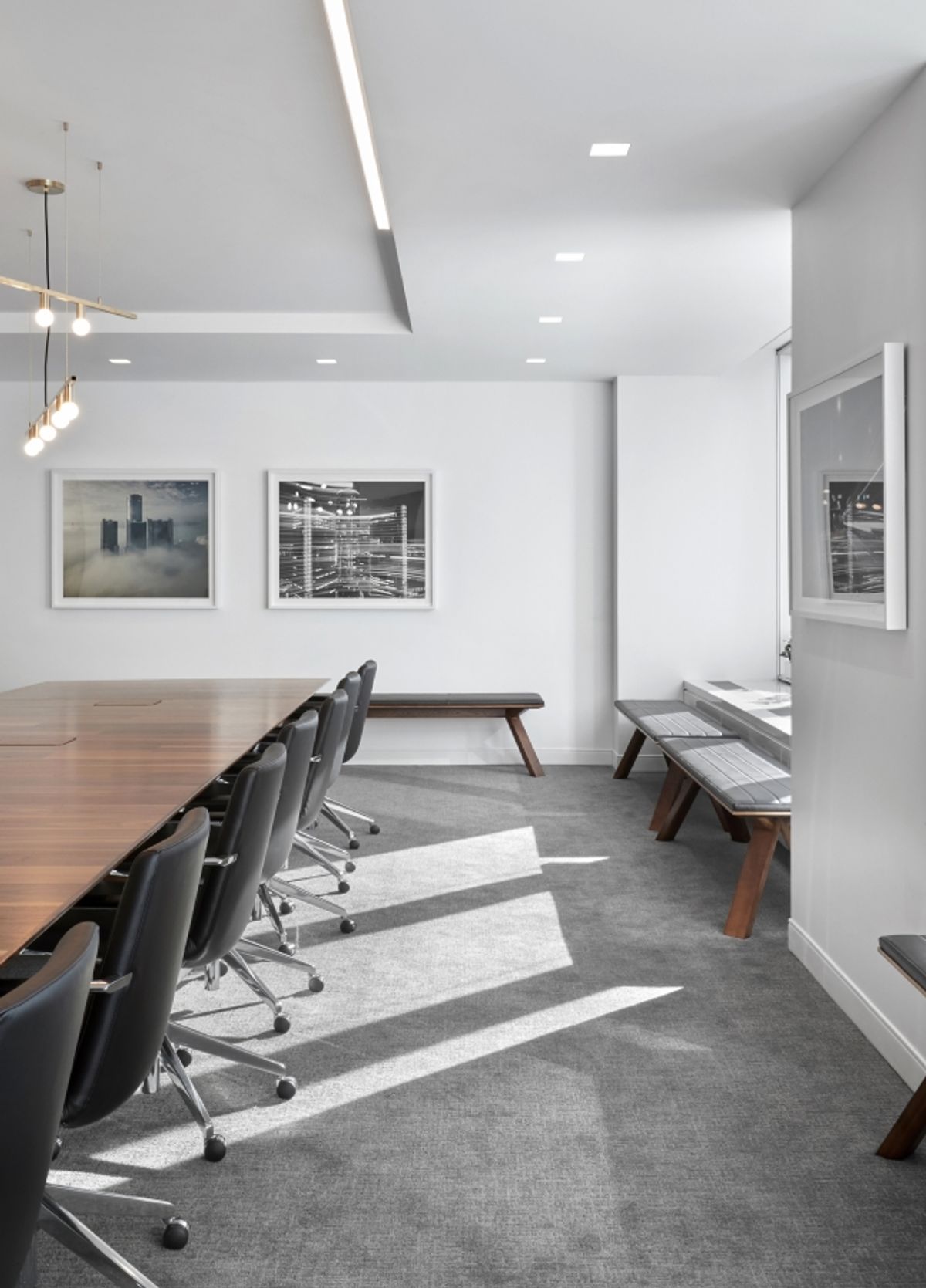 Airy conference room with black and white photos, wood conference table and leather chairs