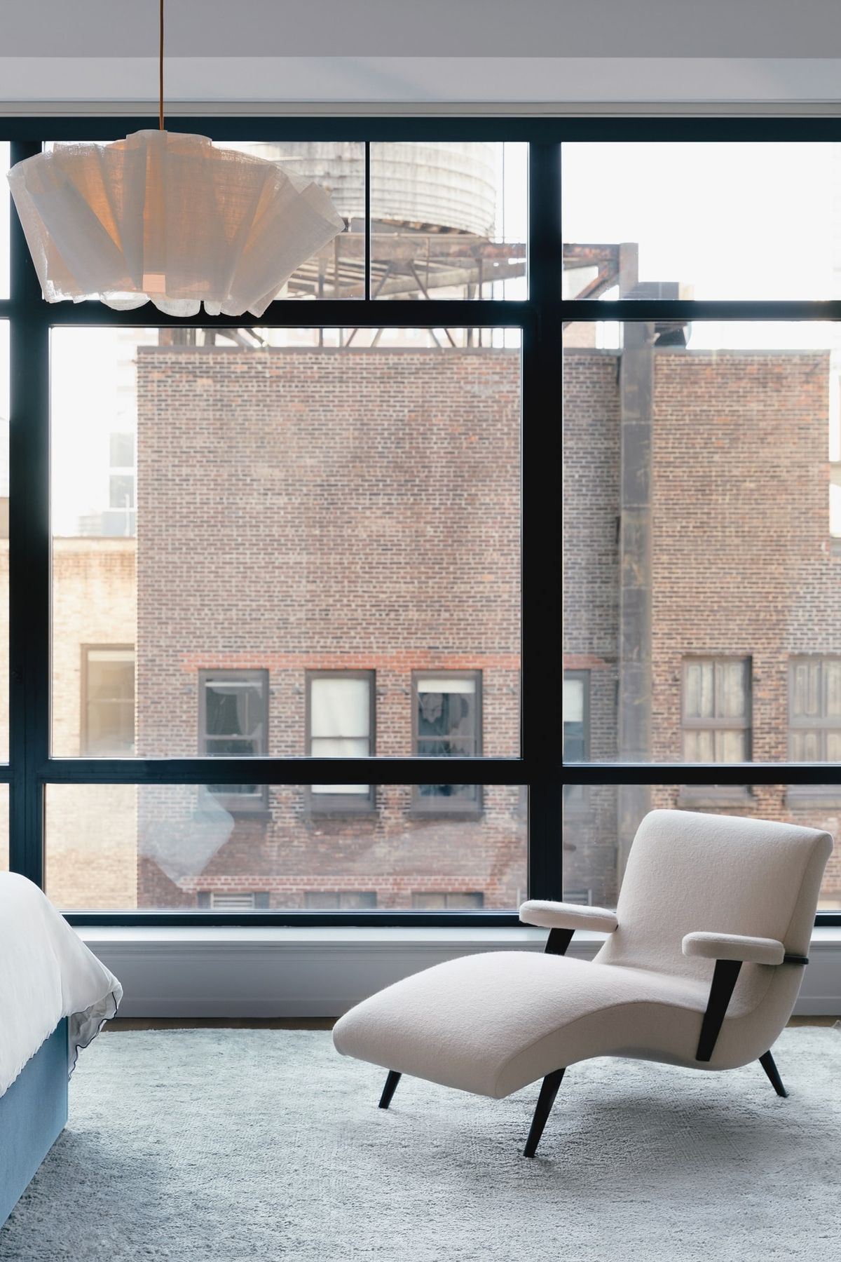 Vignette of cream-colored chaise with view of nearby brick building