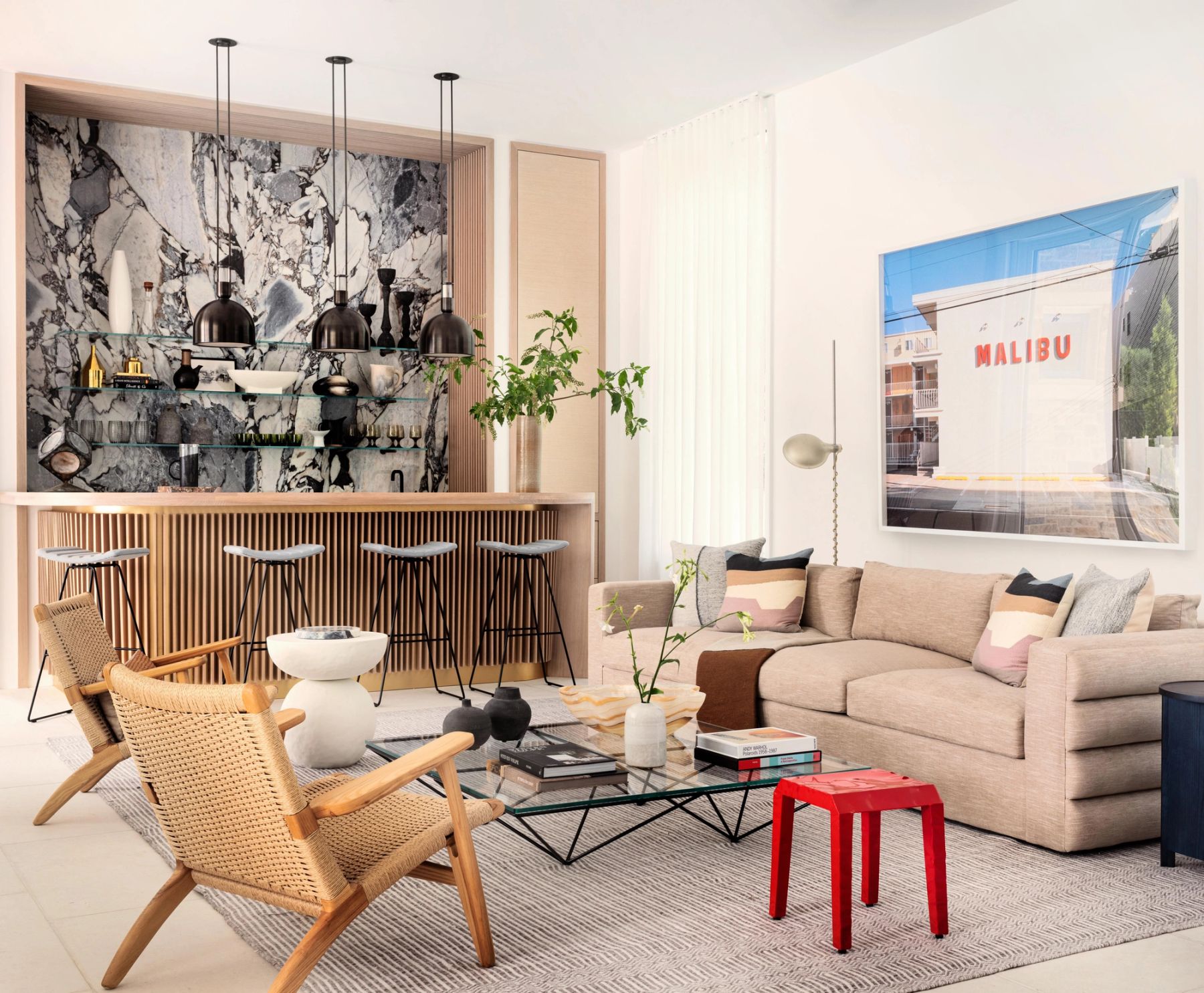 Seating area with sofa and chairs in foreground and wood bar with onyx backsplash in background