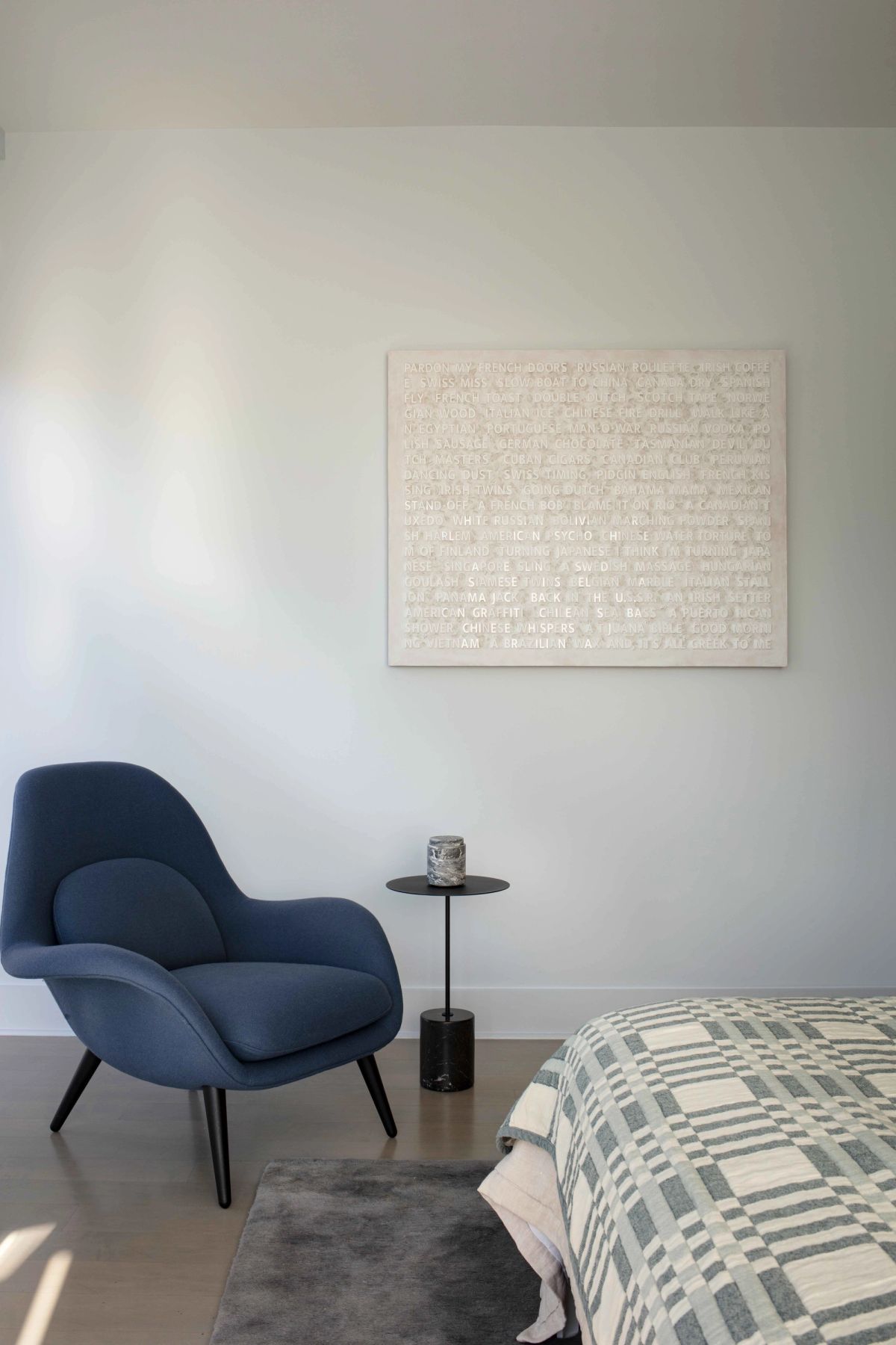 End of bed with accent chair and art against the wall