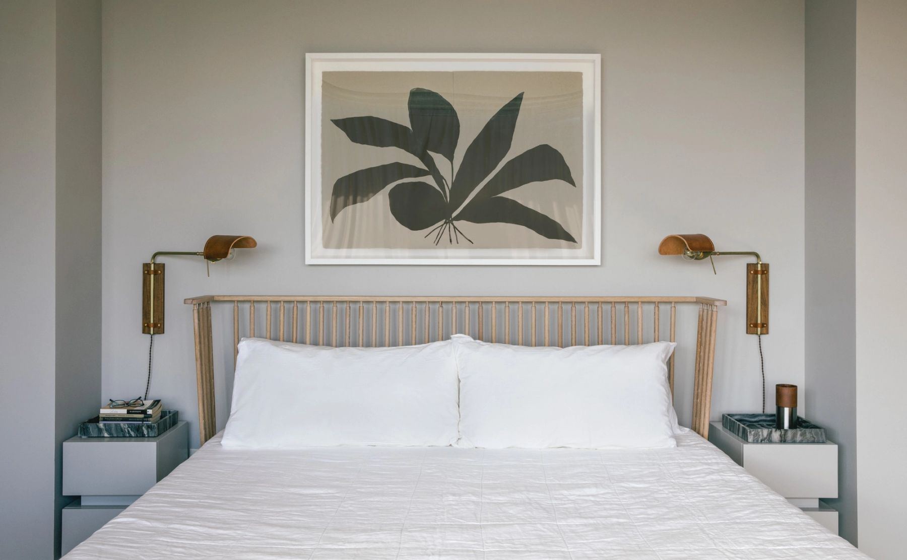 Detail of primary bedroom bed with artwork on wall and matching bedside tables and sconces