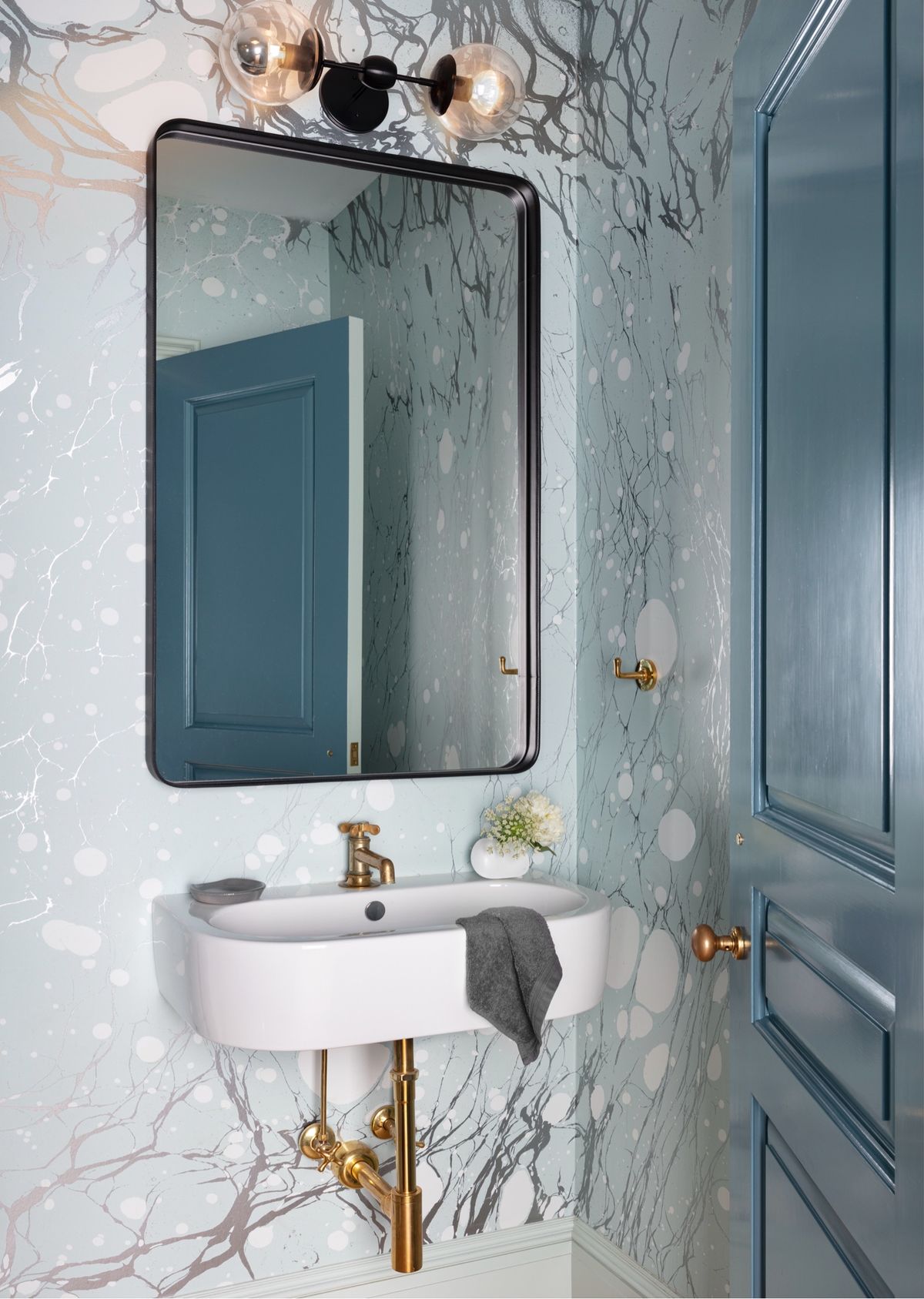 Powder room with blue door and pattern wallpaper