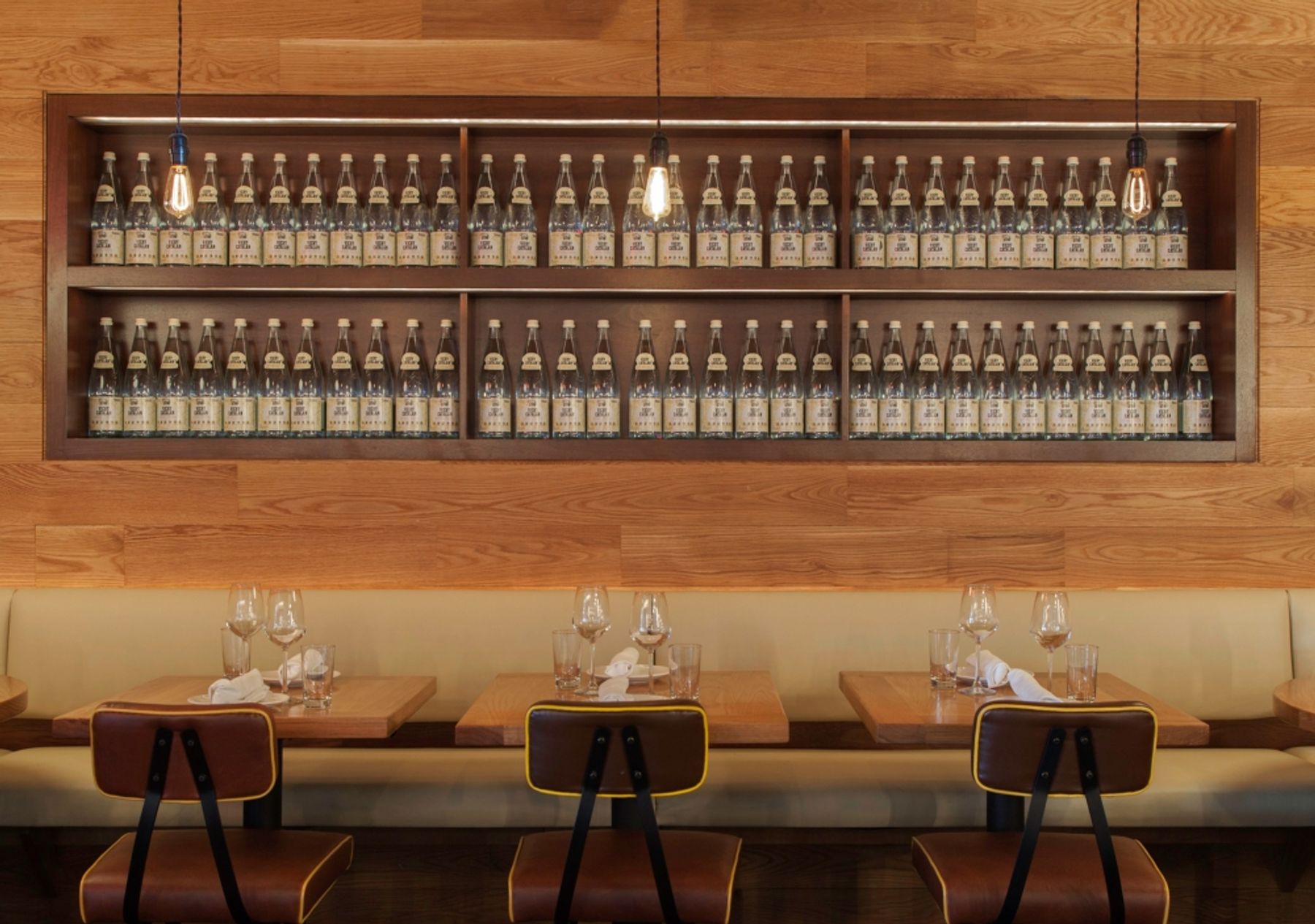 Banquette seating against wall and Edison-lightbulb pendants