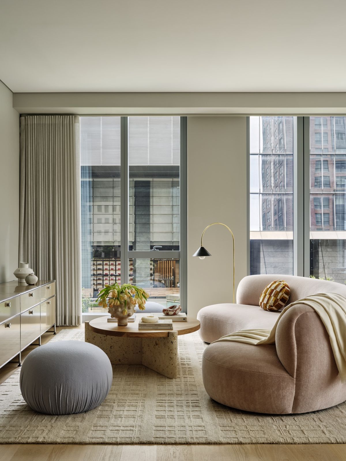 Detail of living room with blush-colored curved sofa, round coffee table and credenza