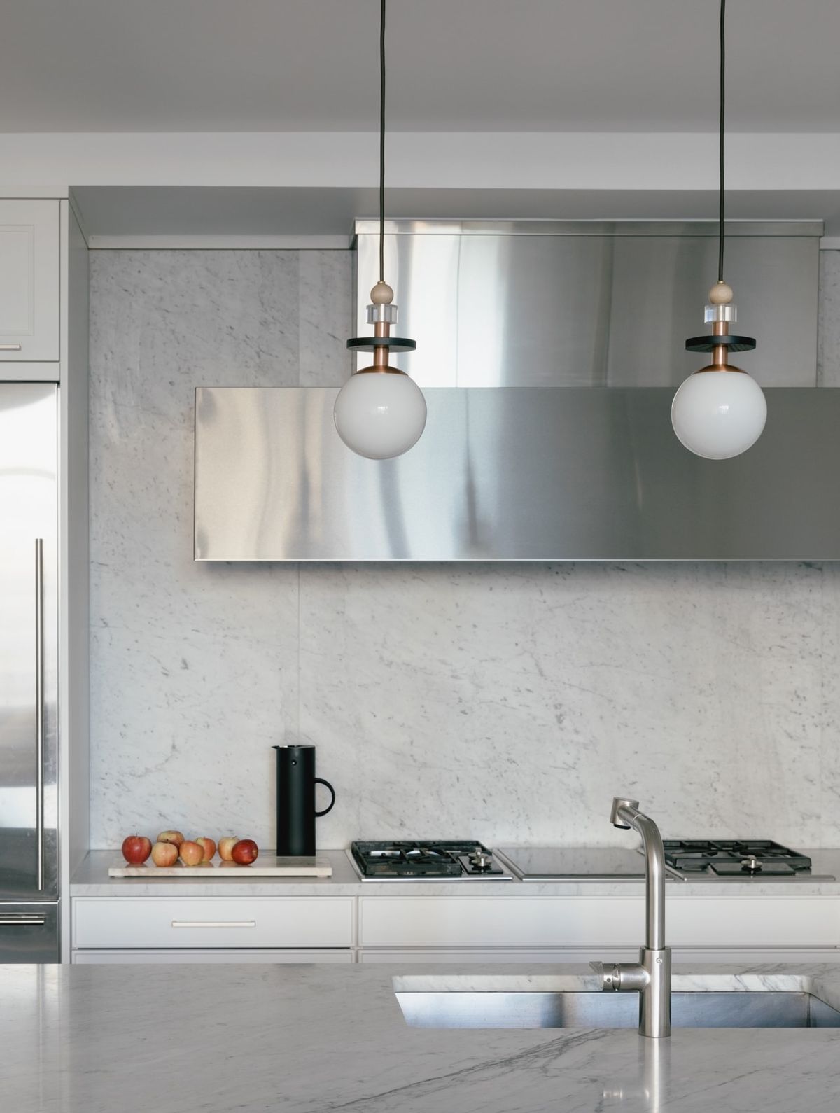 Vignette of marble and stainless steel kitchen with pendant lamps