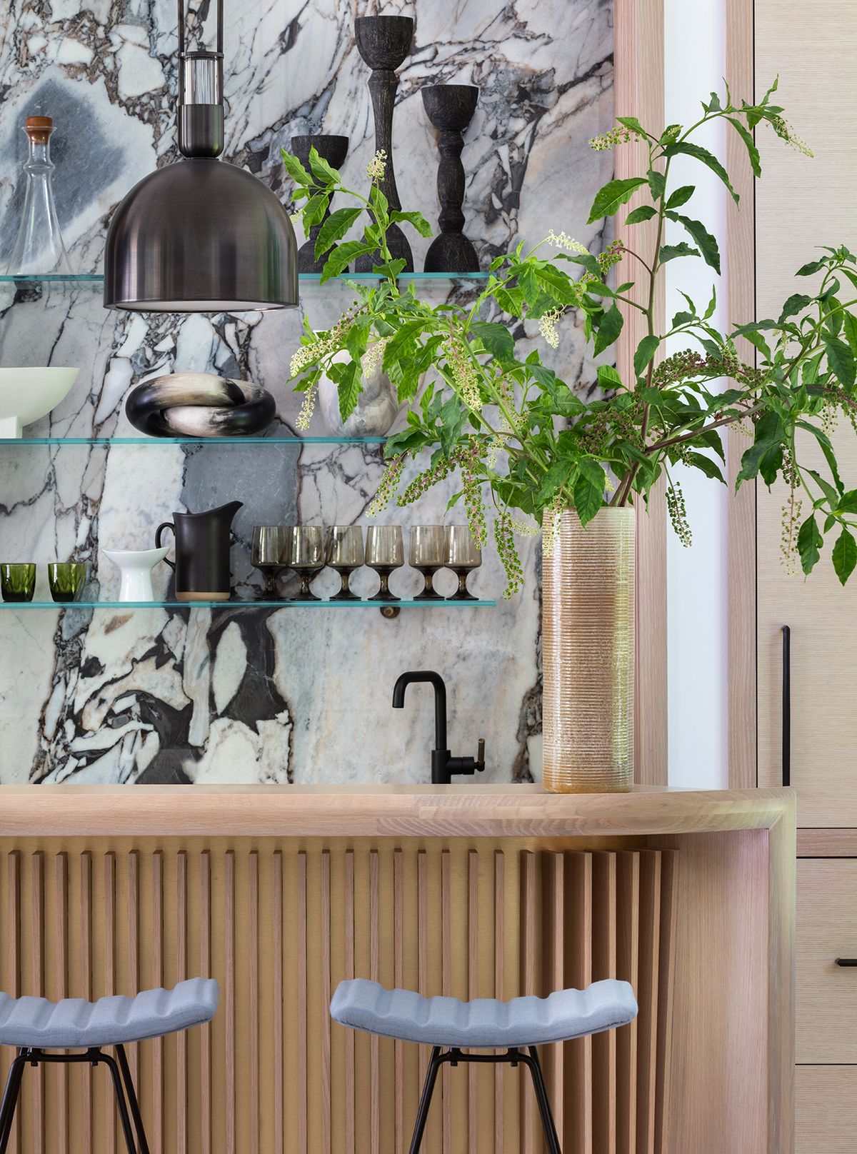 Detail of wood bar with counter stools and onyx backsplash