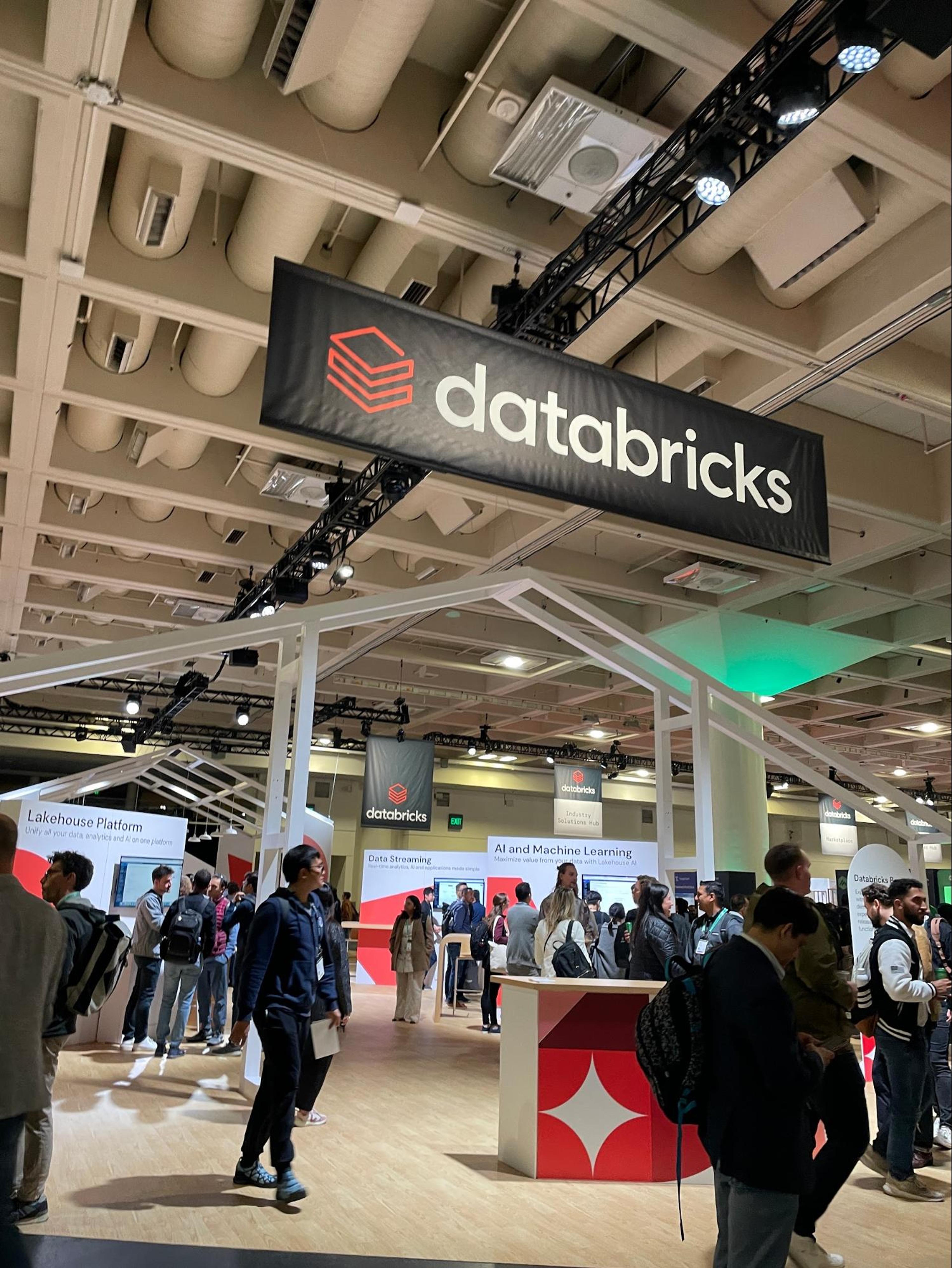 A large group of people are gathered in a room with a sign that says DataBricks.