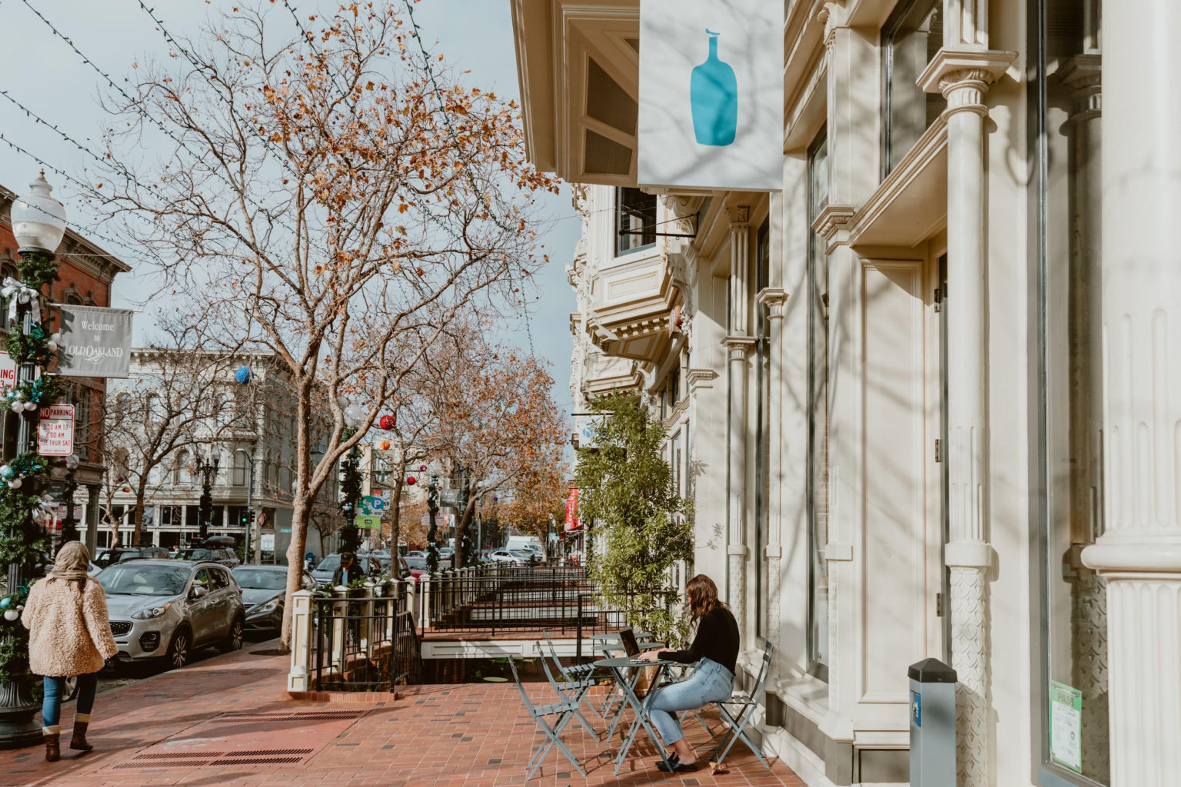 A woman sitting at a table outside a store.