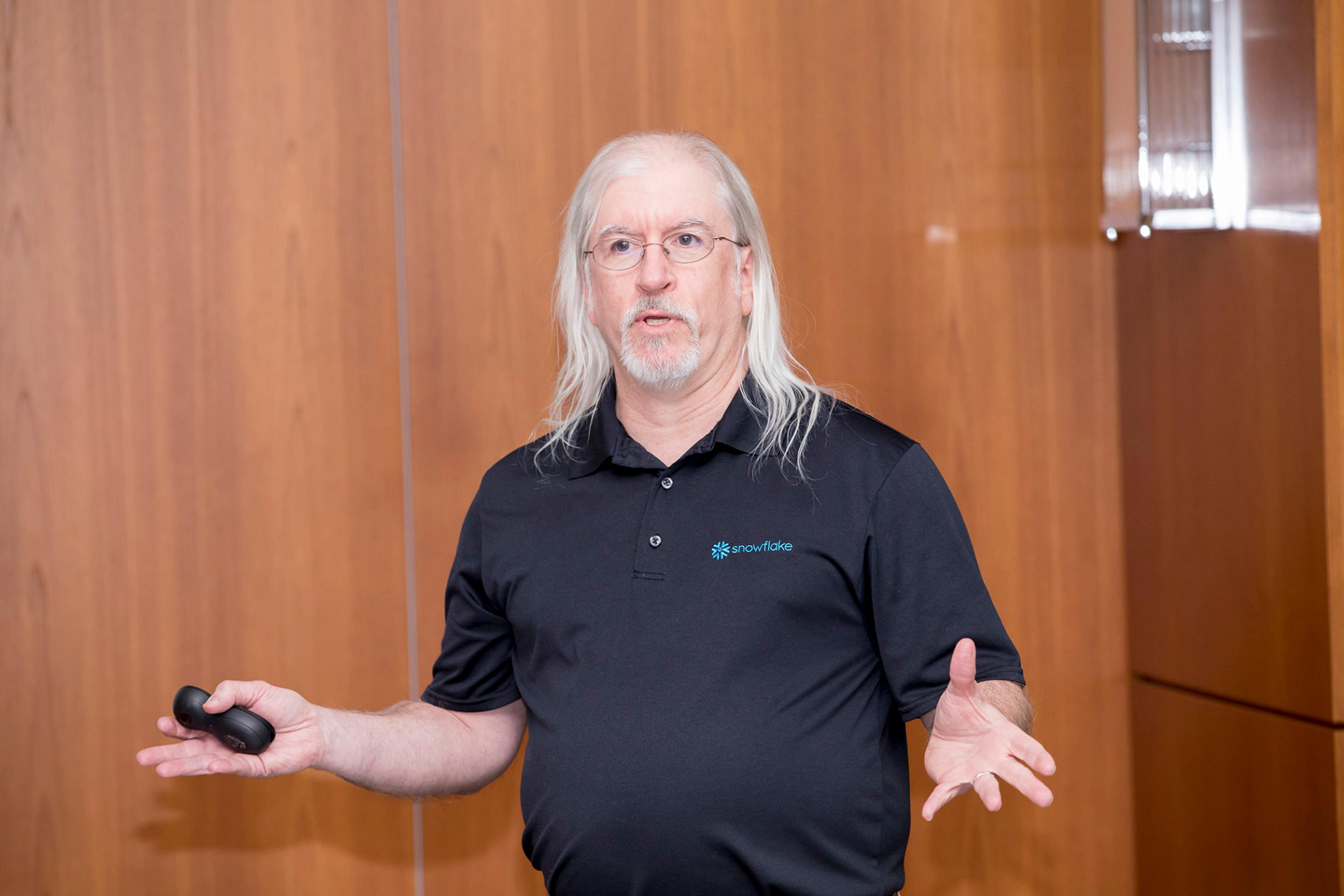 A man with long hair and glasses wearing a black shirt.