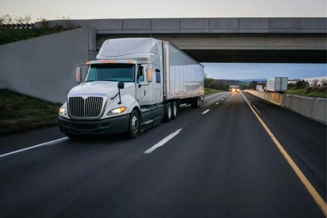 A white semi truck driving on a highway.