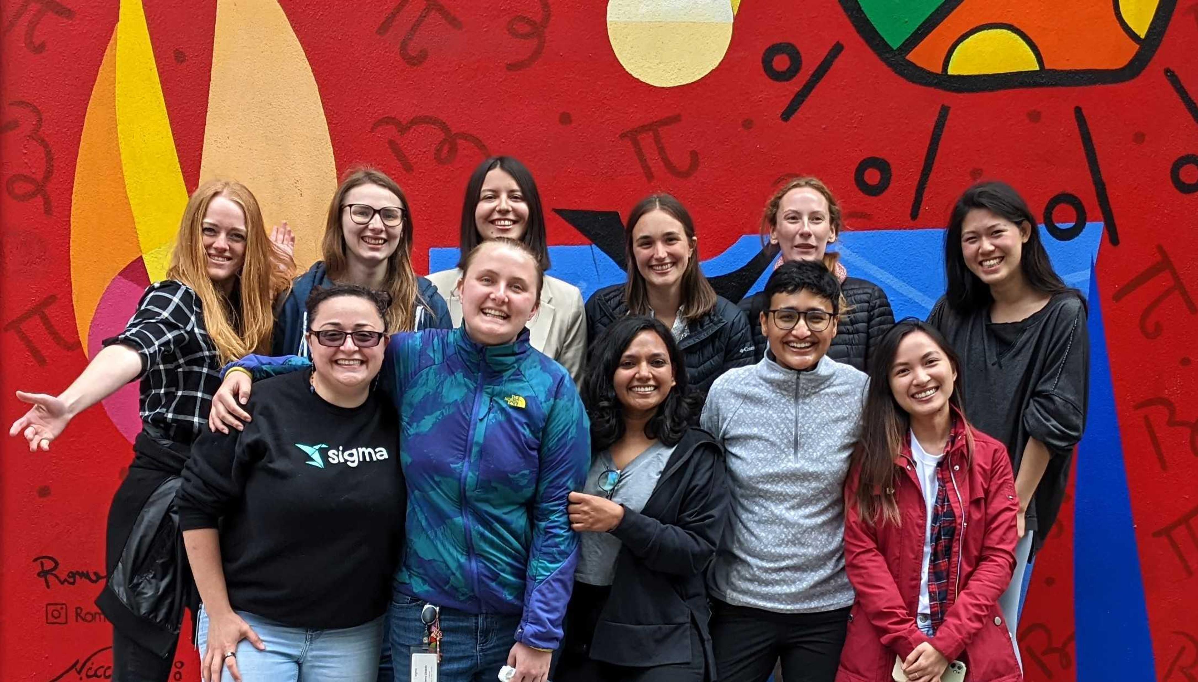 A group of people posing for a picture in front of a red wall.