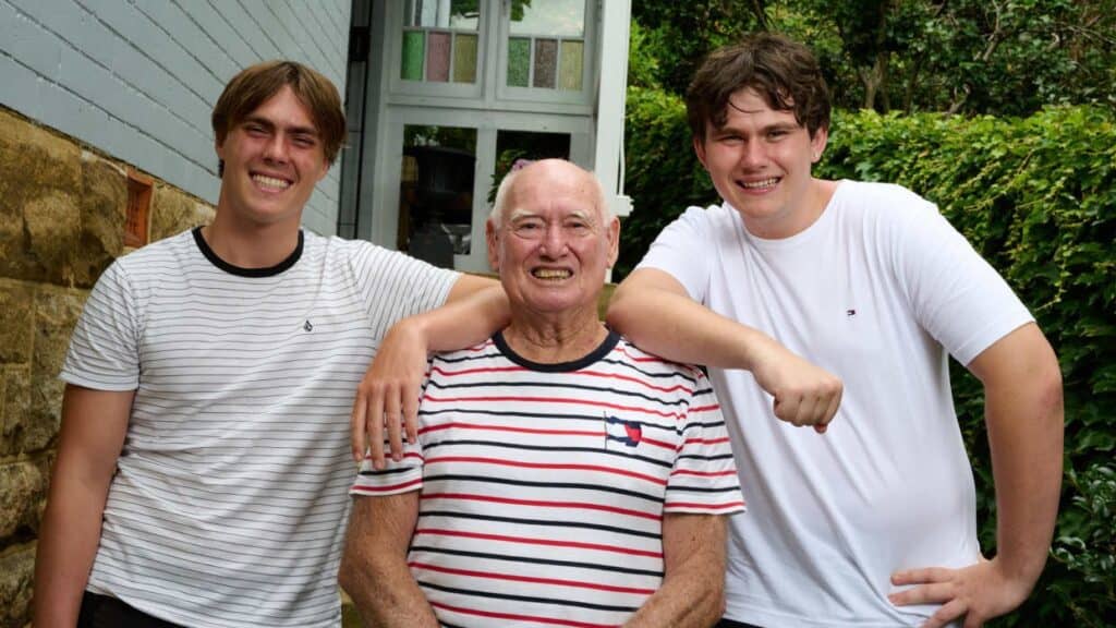 Man standing smiling to camera with his two grandsons by his side