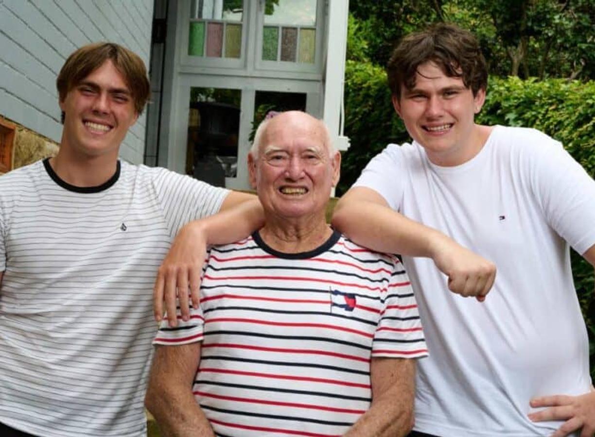 Man standing smiling to camera with his two grandsons by his side