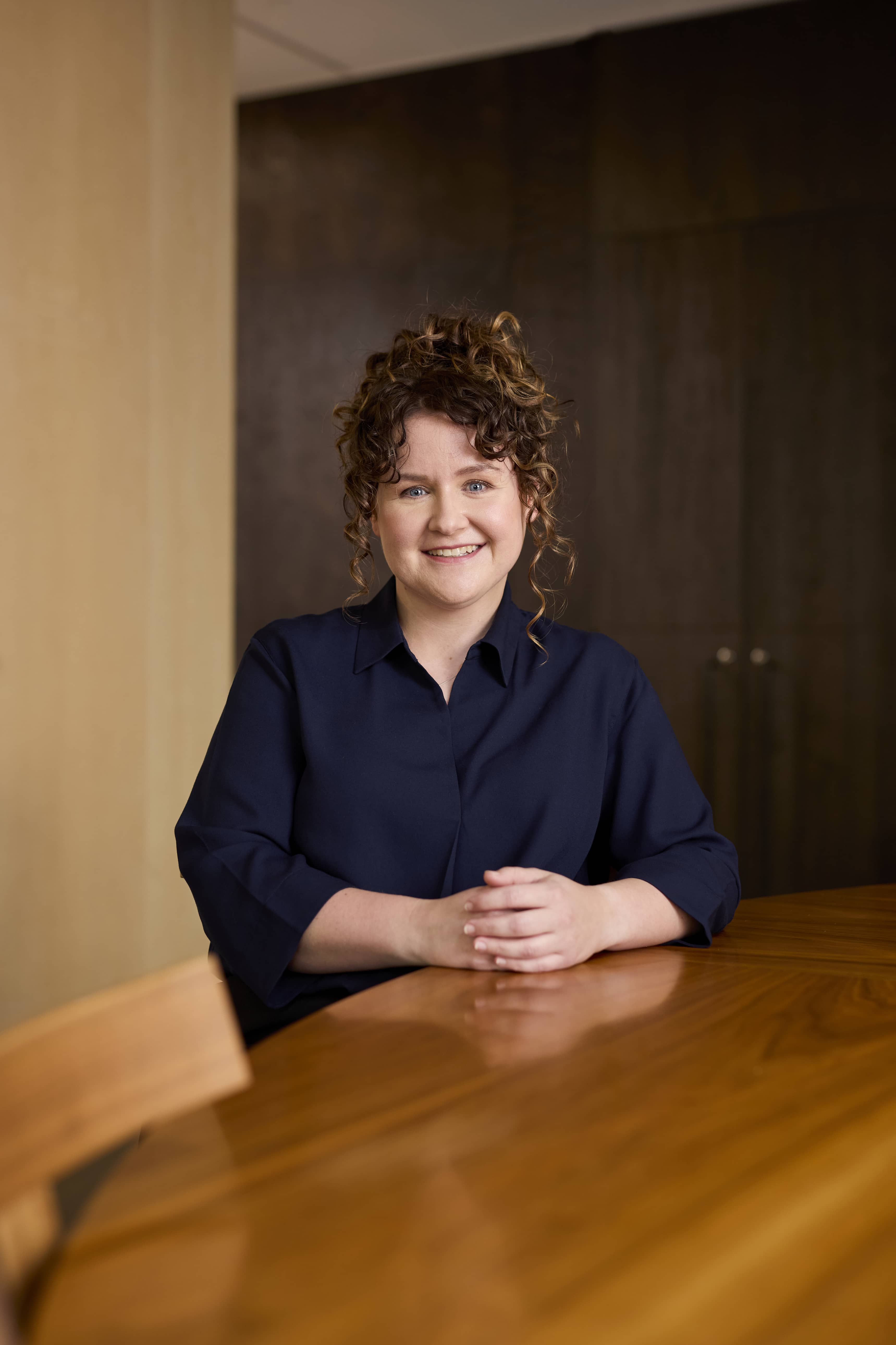Woman sitting in being a wooden table in an office