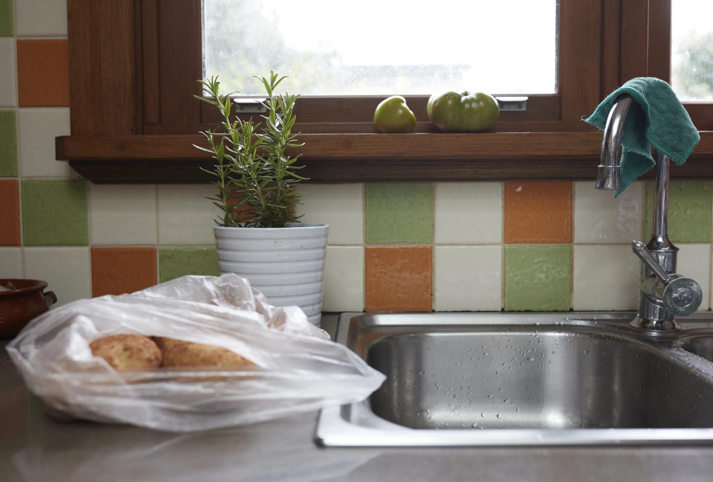 A bag of potatoes sits next to a kitchen sink