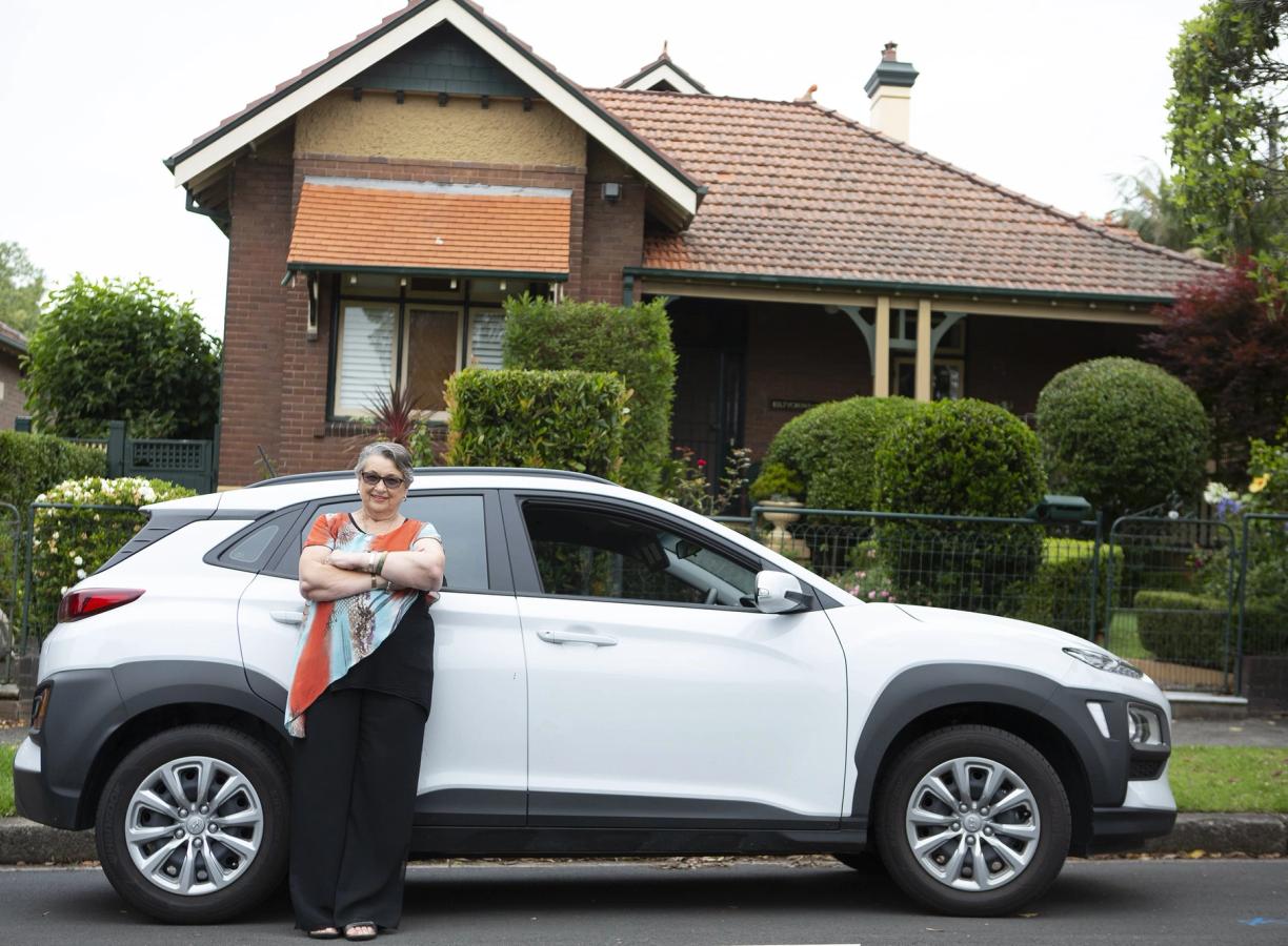 Household Capital customers Lynne standing proudly in front of her new white car
