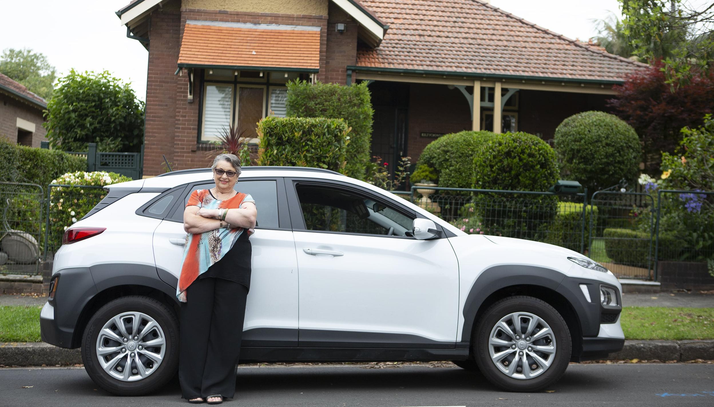 A woman standing in front of a white car