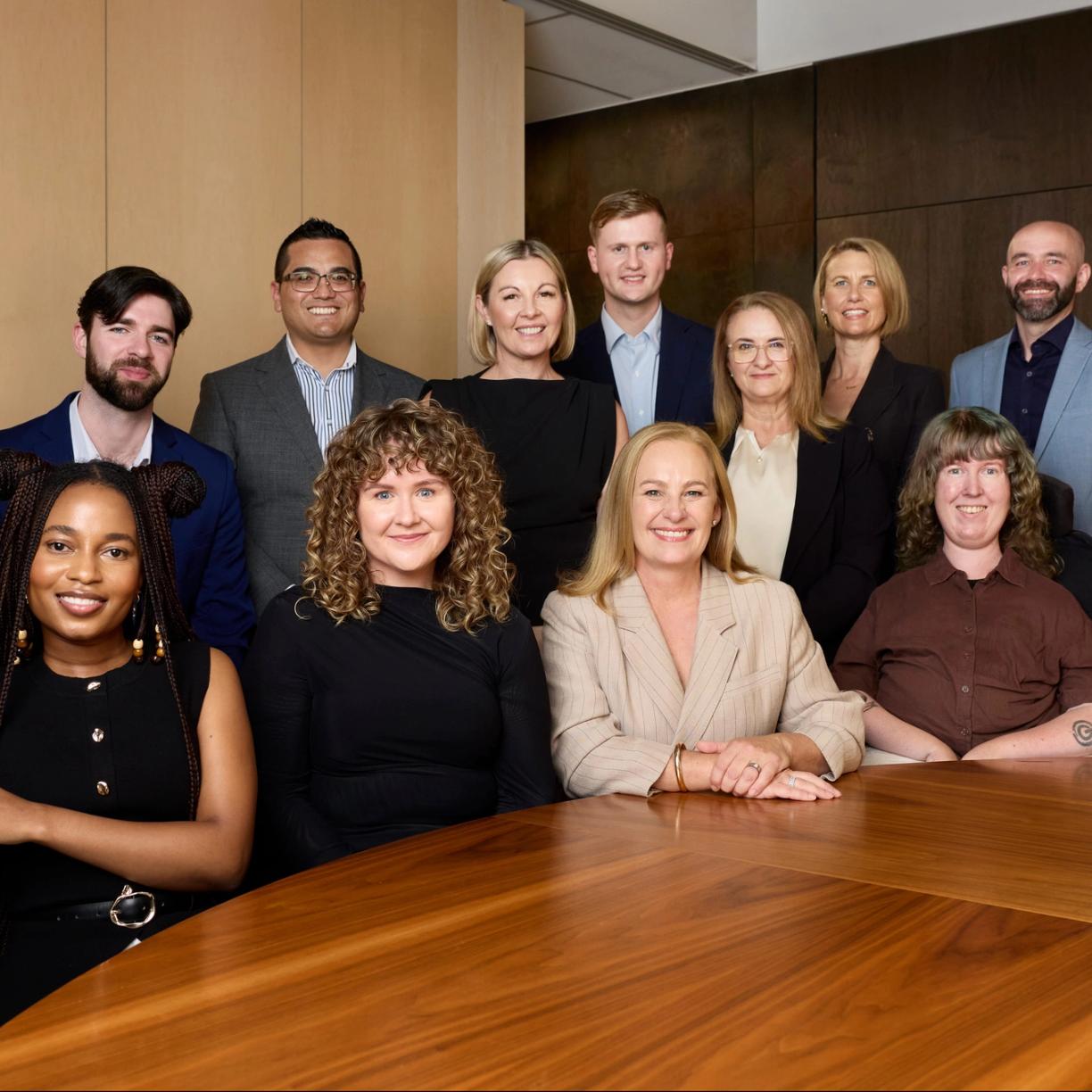 The Household Capital broker team sit across a table together smiling to camera
