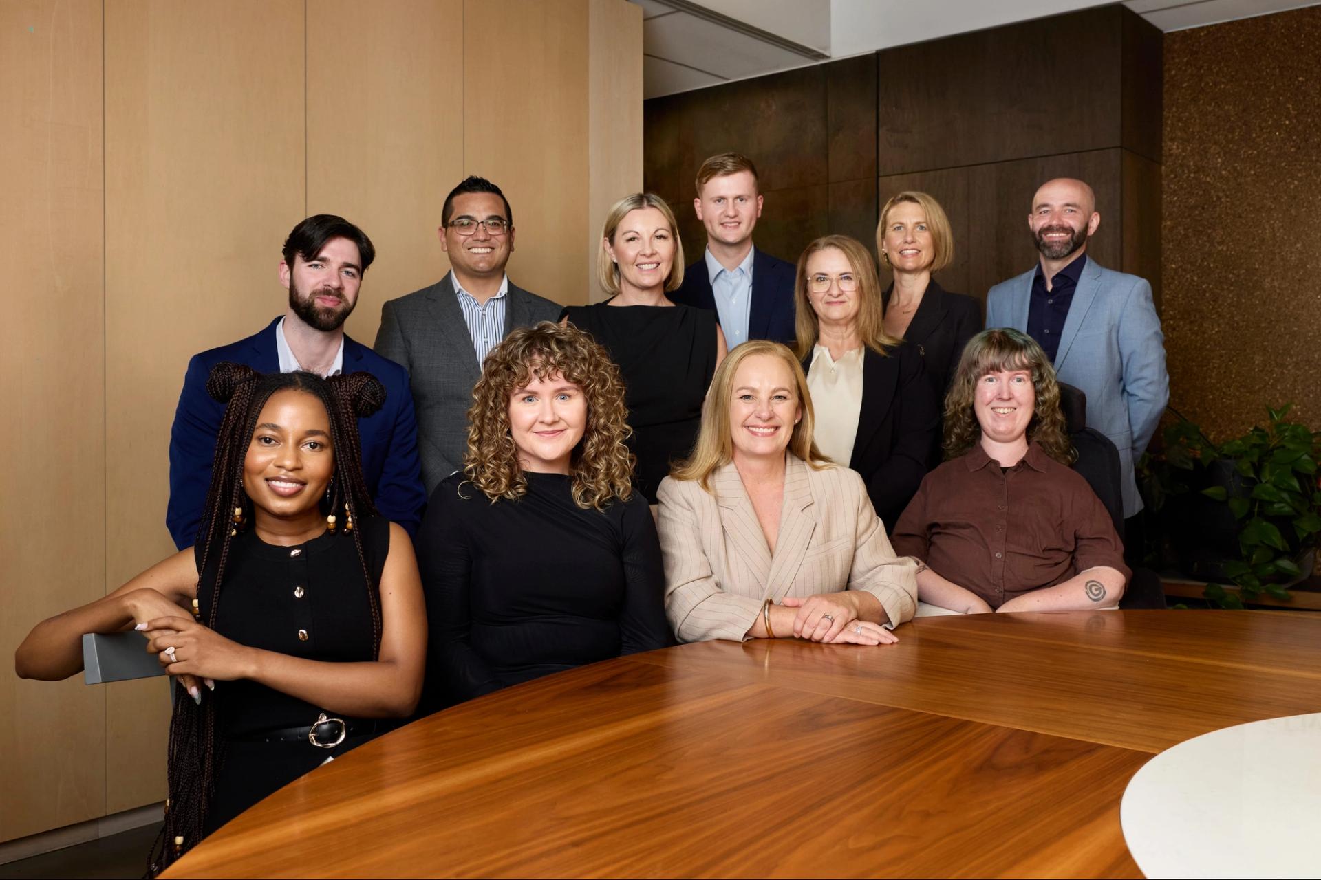 The Household Capital broker team sit around a table and smile to camera