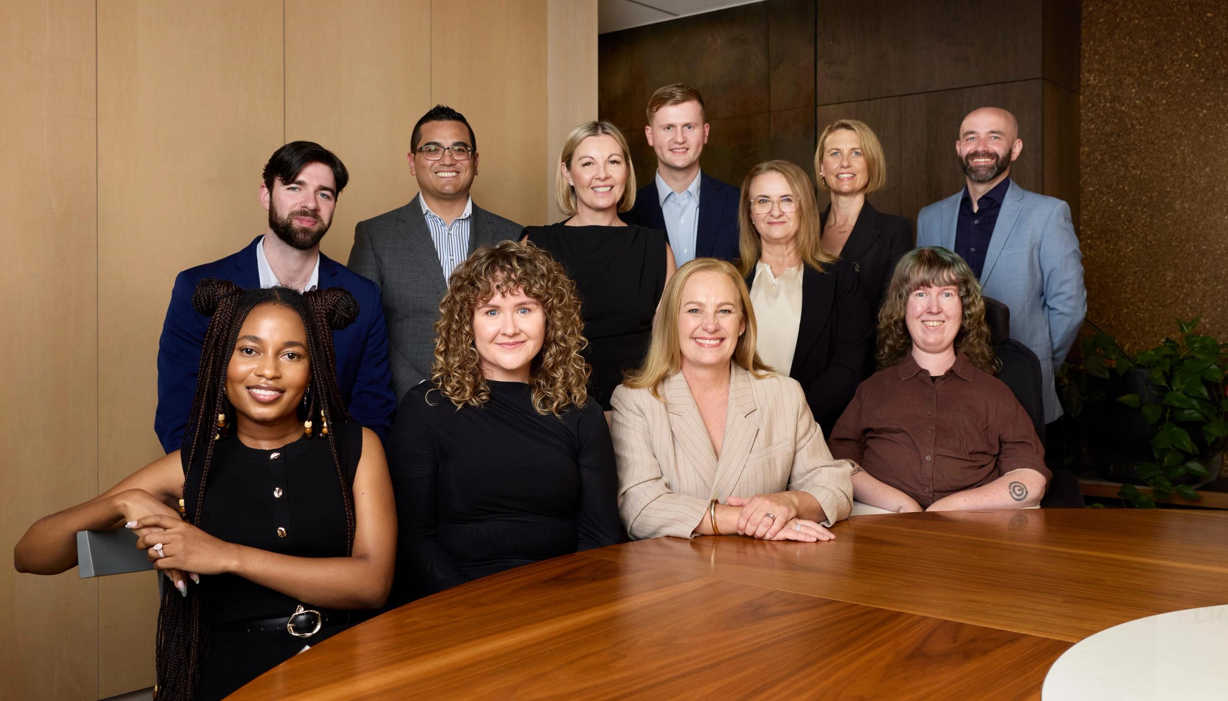 The Household Capital broker team sit around a table and smile to camera