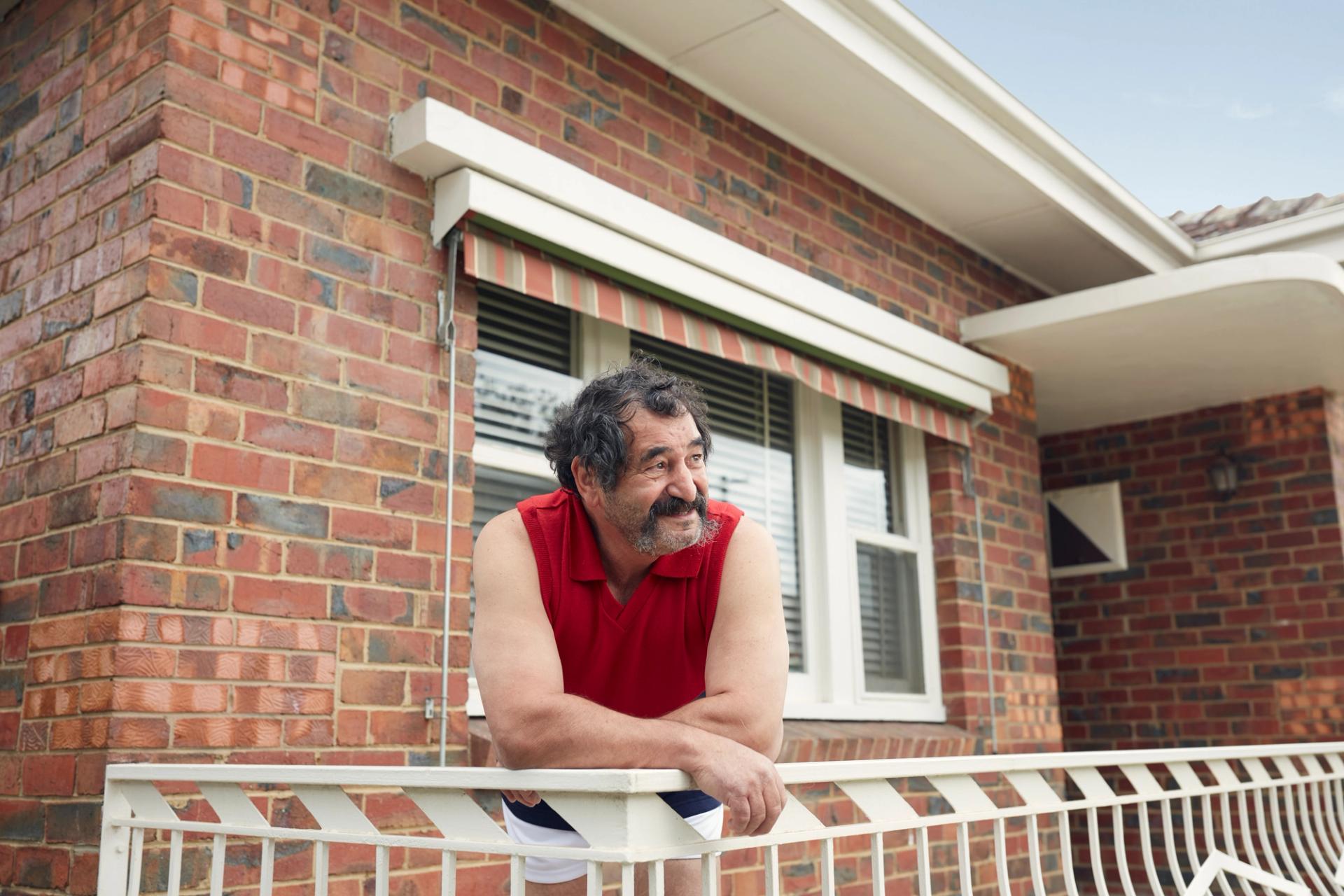 A man leaning over his front veranda railing