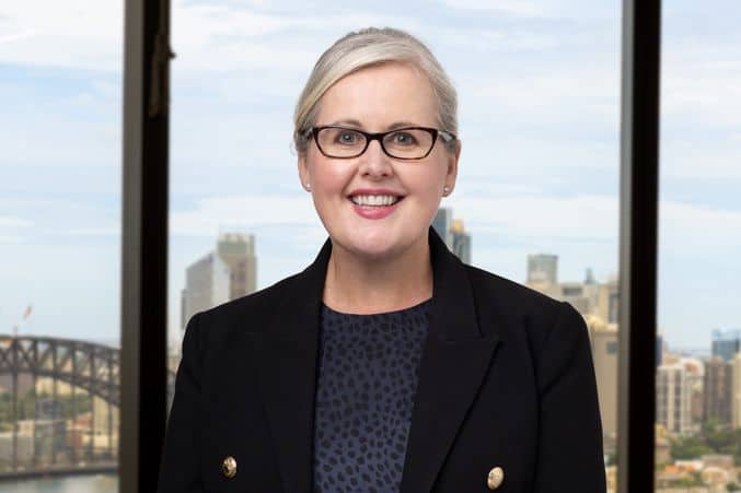 Woman standing in front of a window looking out on the Sydney harbour