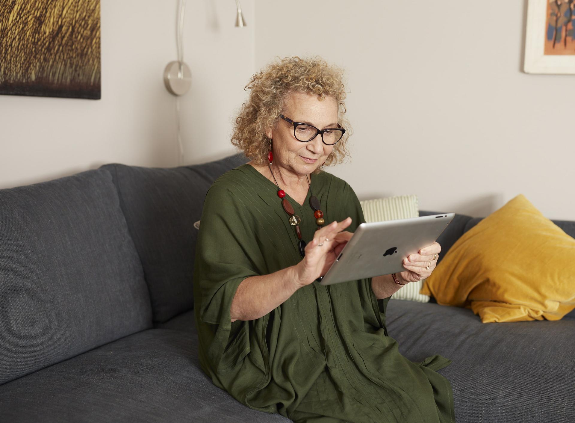 Woman sitting on a couch looking at an iPad