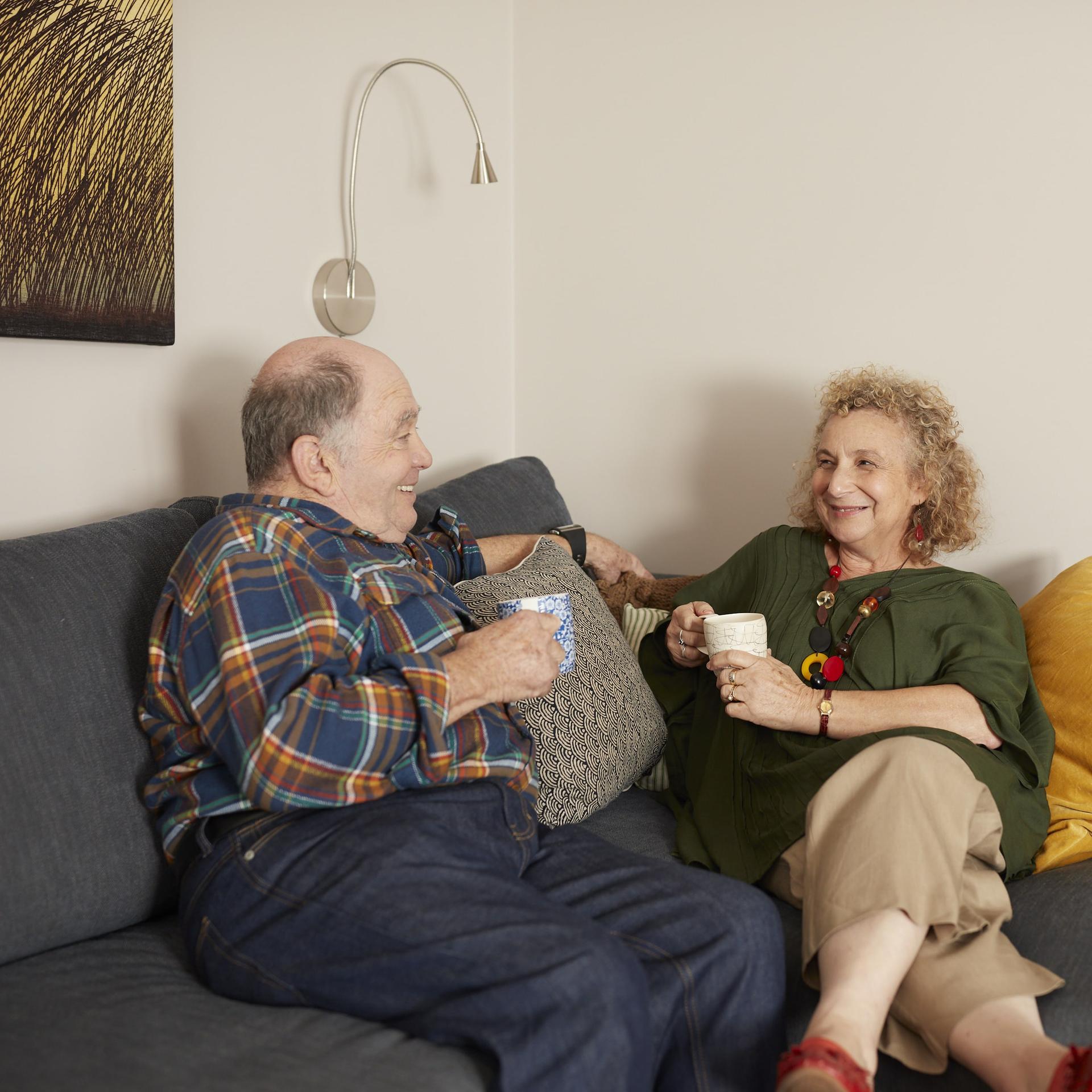 Couple sitting on a couch drinking a cup of tea