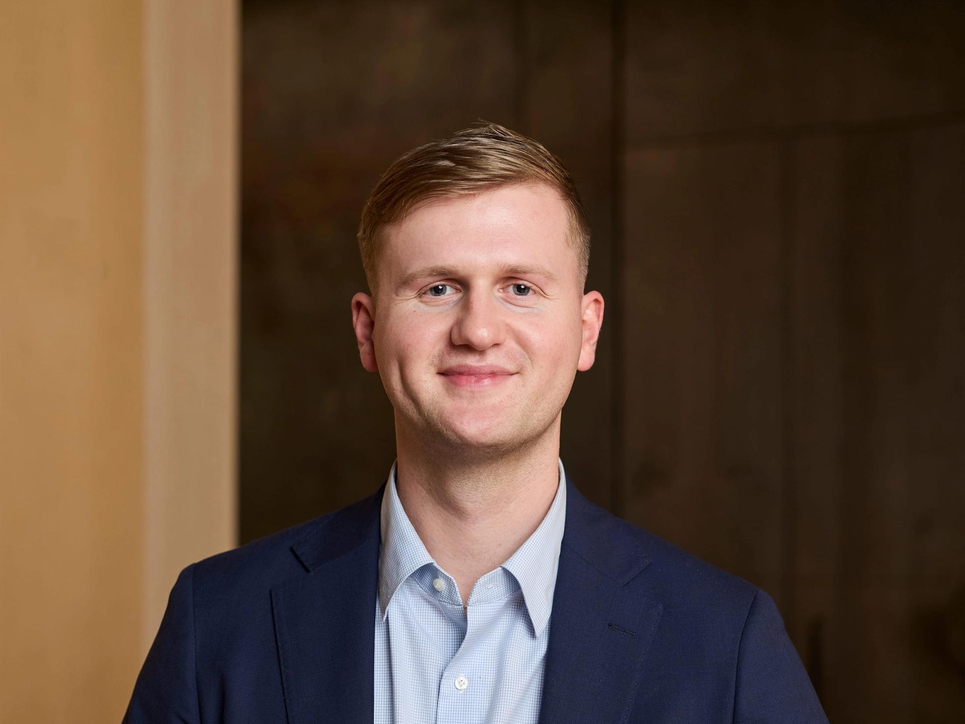 A man sits at a table and smiles to camera