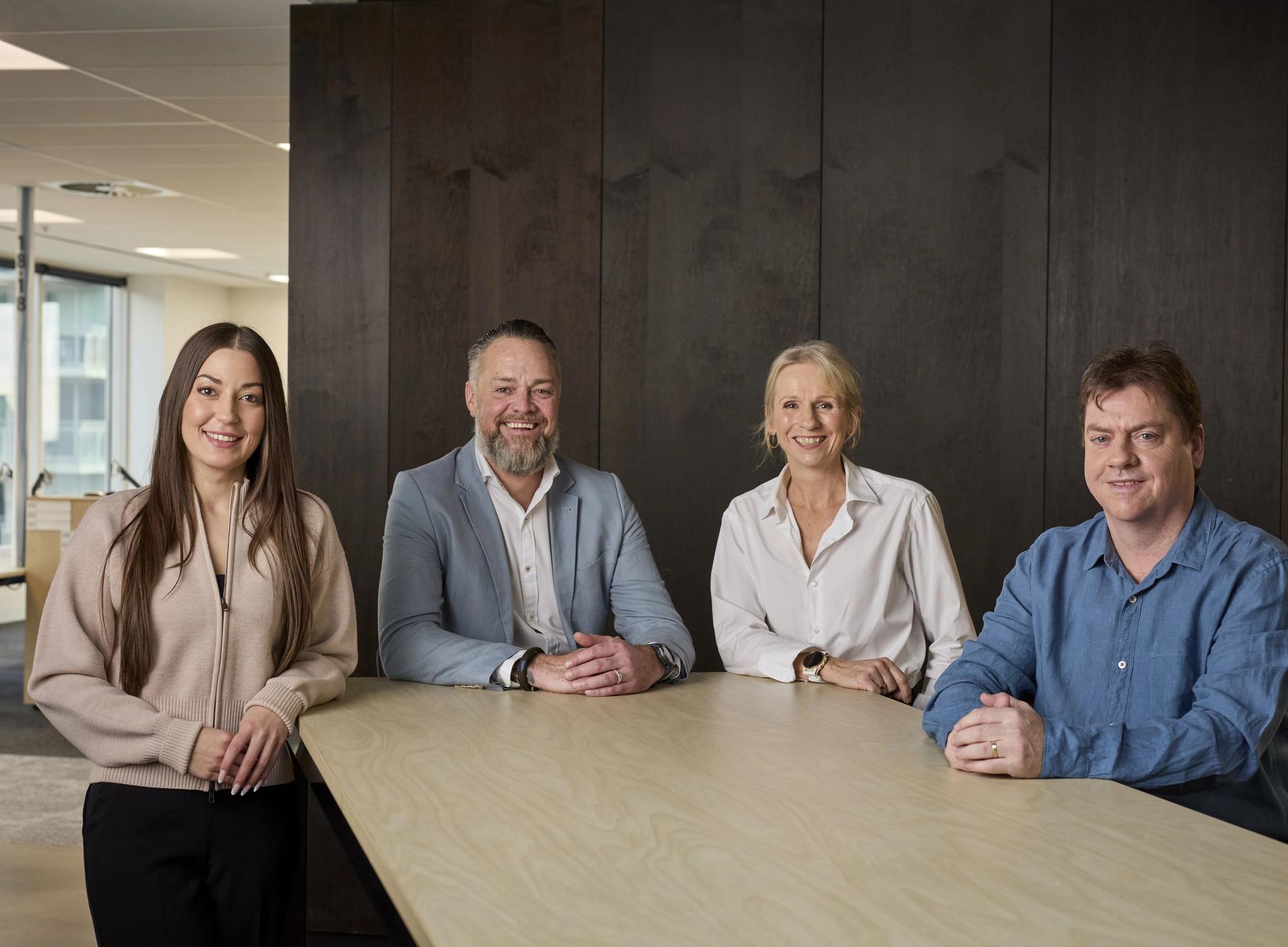 Group of four people standing behind a desk in a modern office