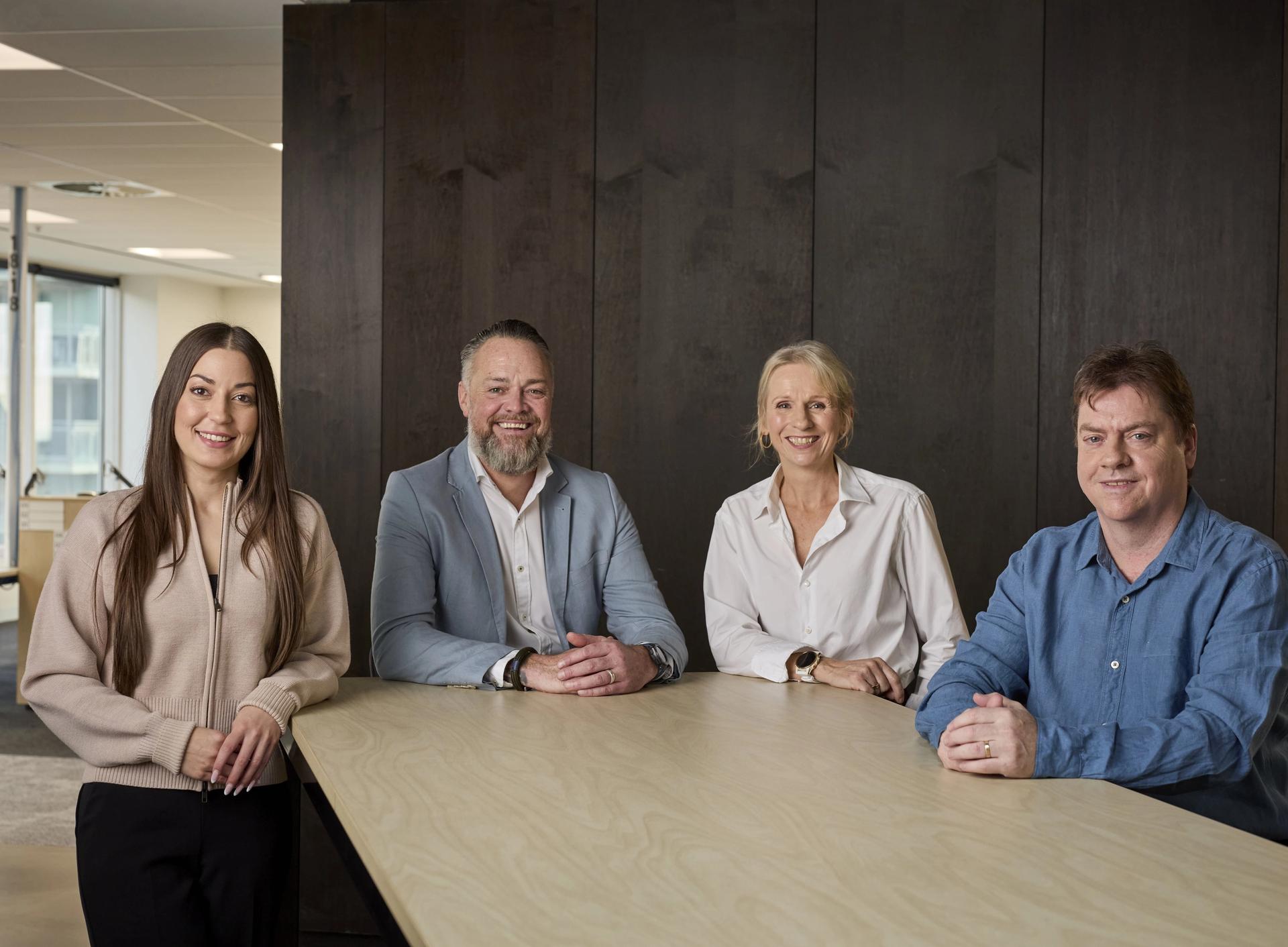 Group of four people standing behind a desk