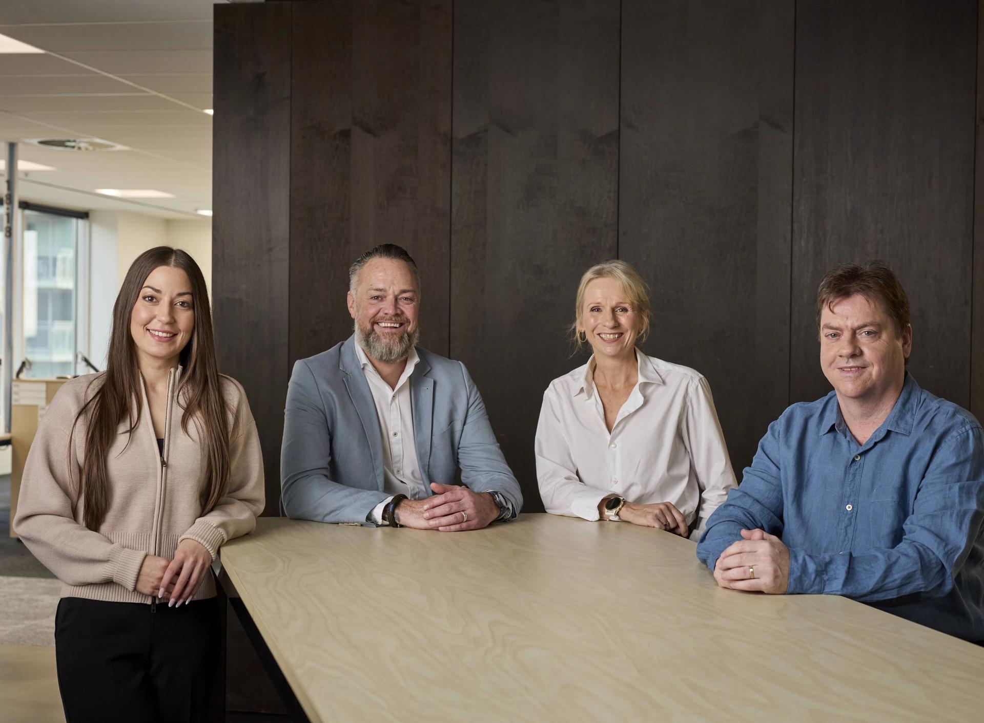 Group of four people standing behind a desk