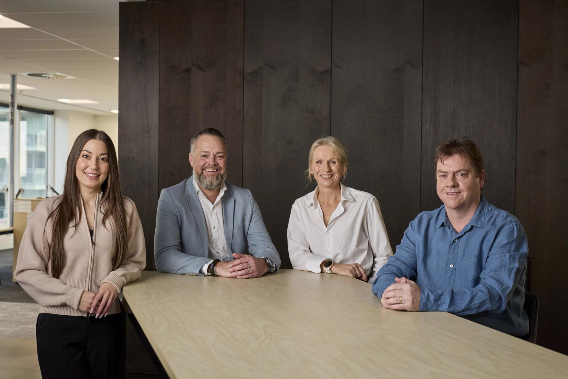 Household Capital Sales team sit around a table smiling to camera